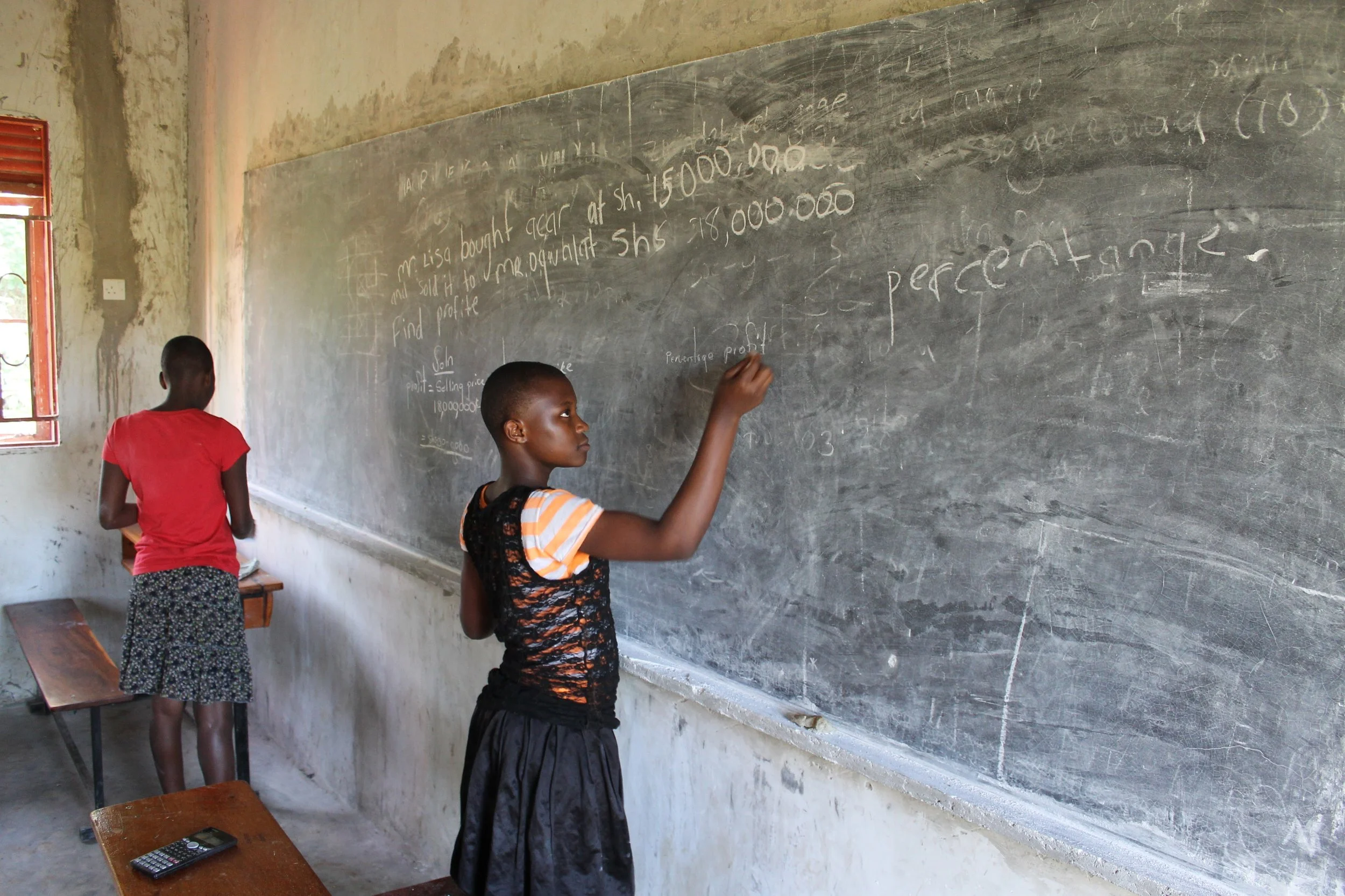 Female Middle School Students at Bulamu working after class on math problems.