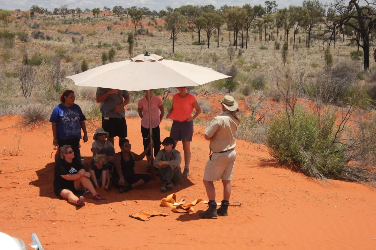 Trainees gather under shade to hear the task's instruction.