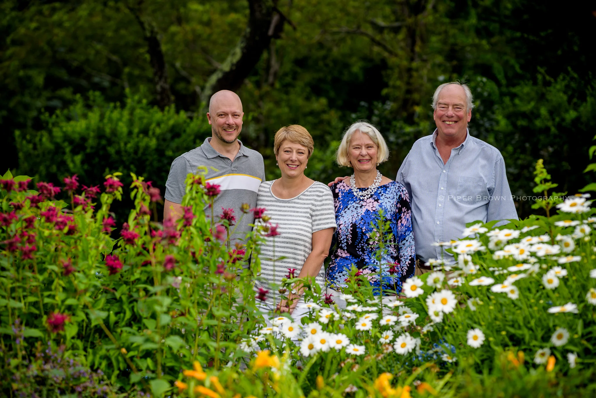 Family of four - bald man, blonde woman, older woman, older man looking straight at camera