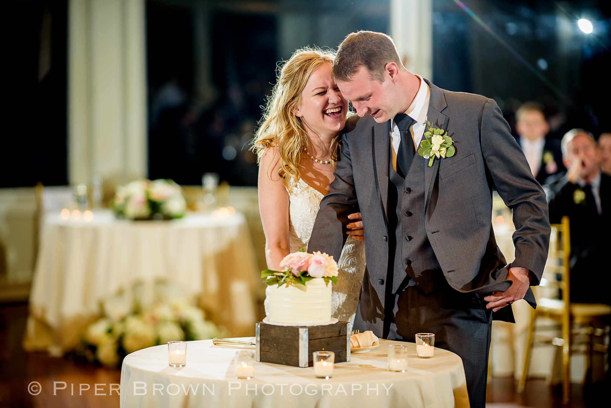Bride laughing and Groom smiling cutting wedding cake 