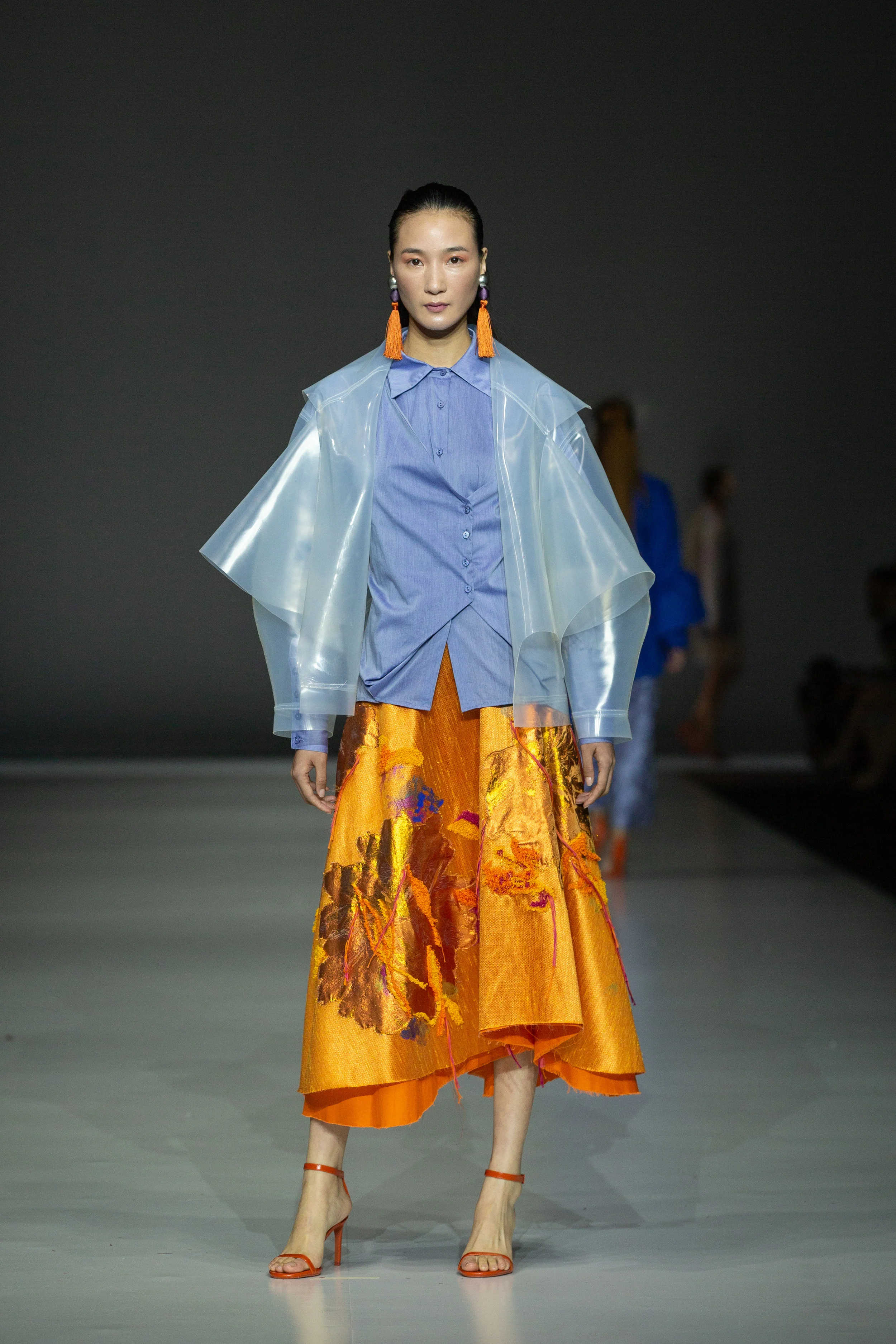 Lucia Alcaina Up-cycled flared skirt made from end-of-rolls and factory surplus waste, embellished with embroidered organza scraps, threads, needle punching and hand-painting, paired with up-cycled tailored shirt with origami detailing made with cut-and-sew damaged textiles, and layered with up-cycled oversized silicone coat
