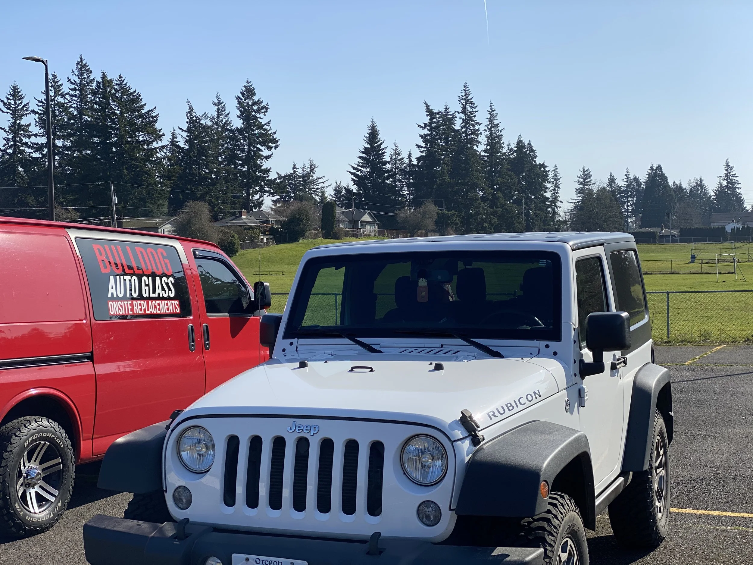 Jeep Wrangler windshield replacement service in Gresham, Oregon, with a technician installing new auto glass on a Wrangler in a parking lot.