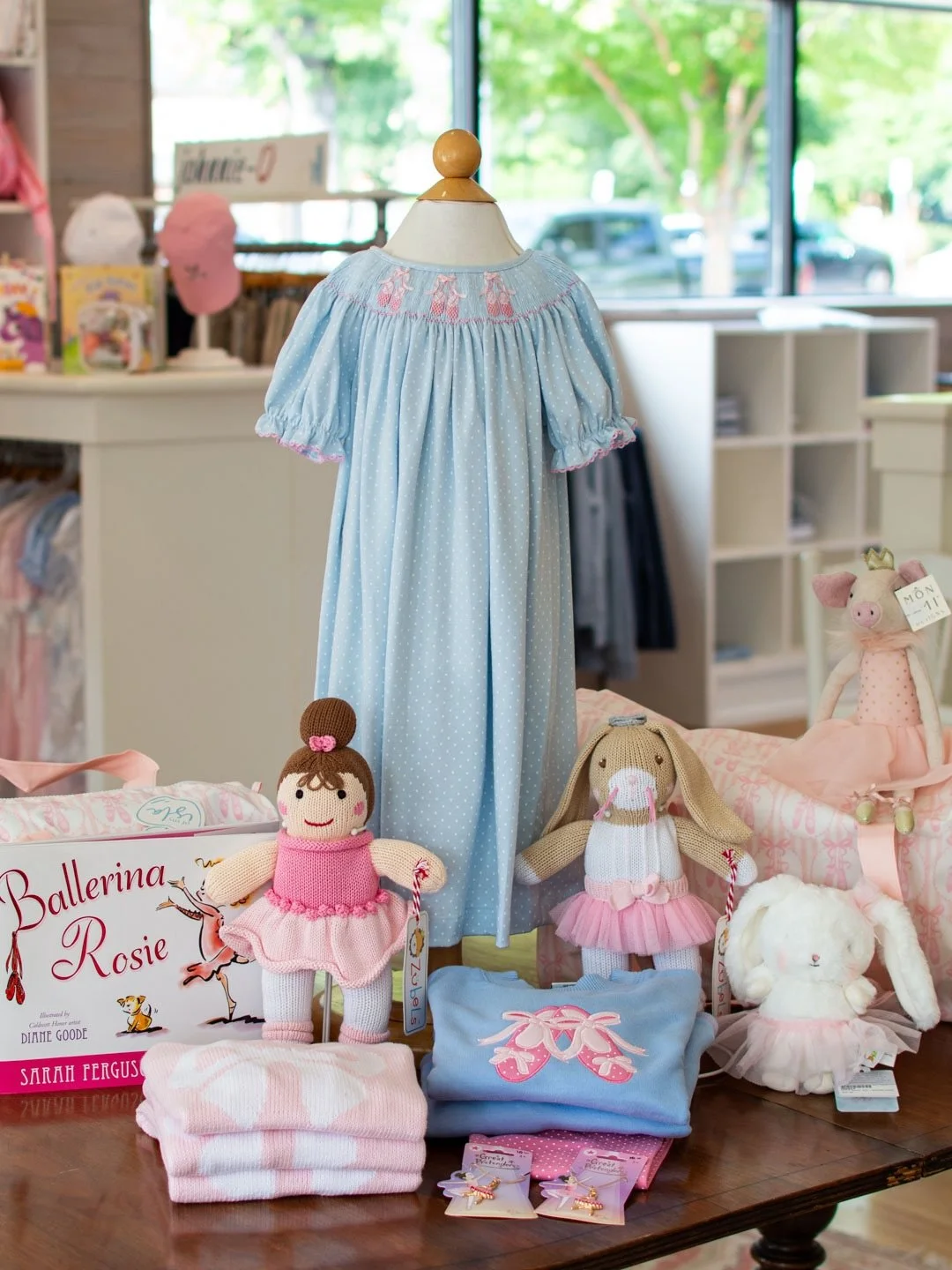 A table full of ballerinas on our front display this week! 🩰 Smocked dress from Petit Bebe with pink bow sweater from Little English and ballet slipper top from Luigi.