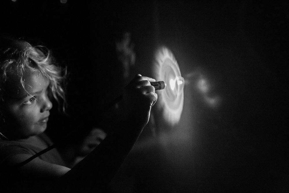 Black and white image of girl writing on glow in the dark wall