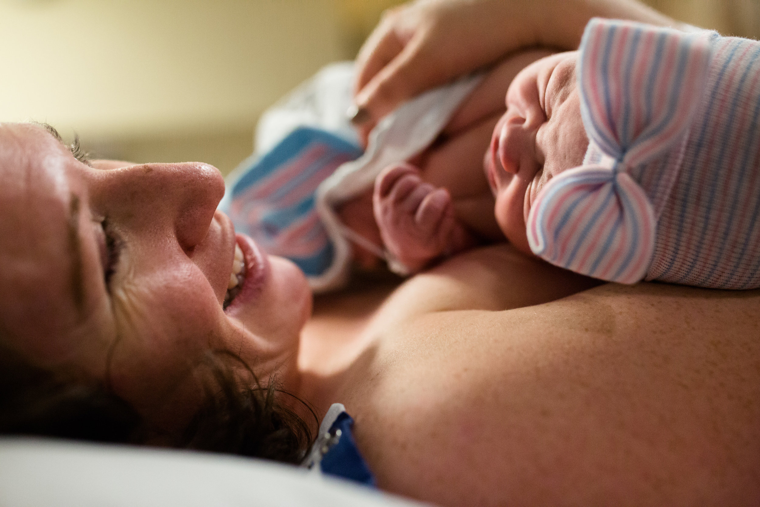 mother holding baby after birth and smiling at husband