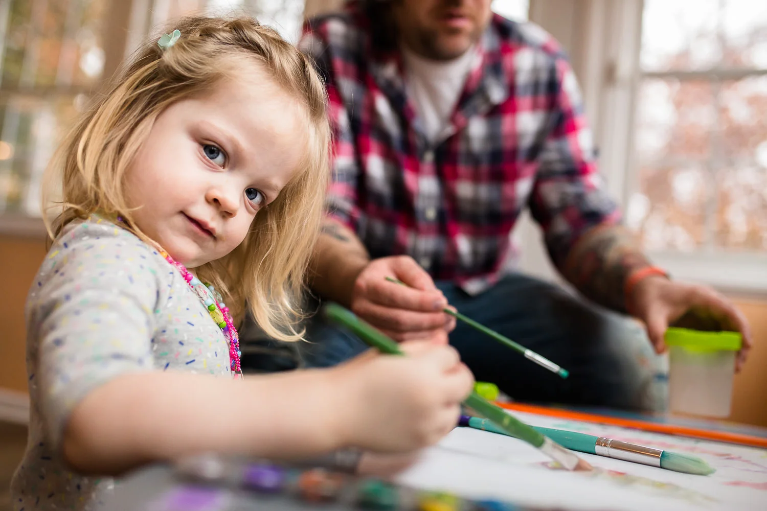 toddler paitning with water colors with her dad