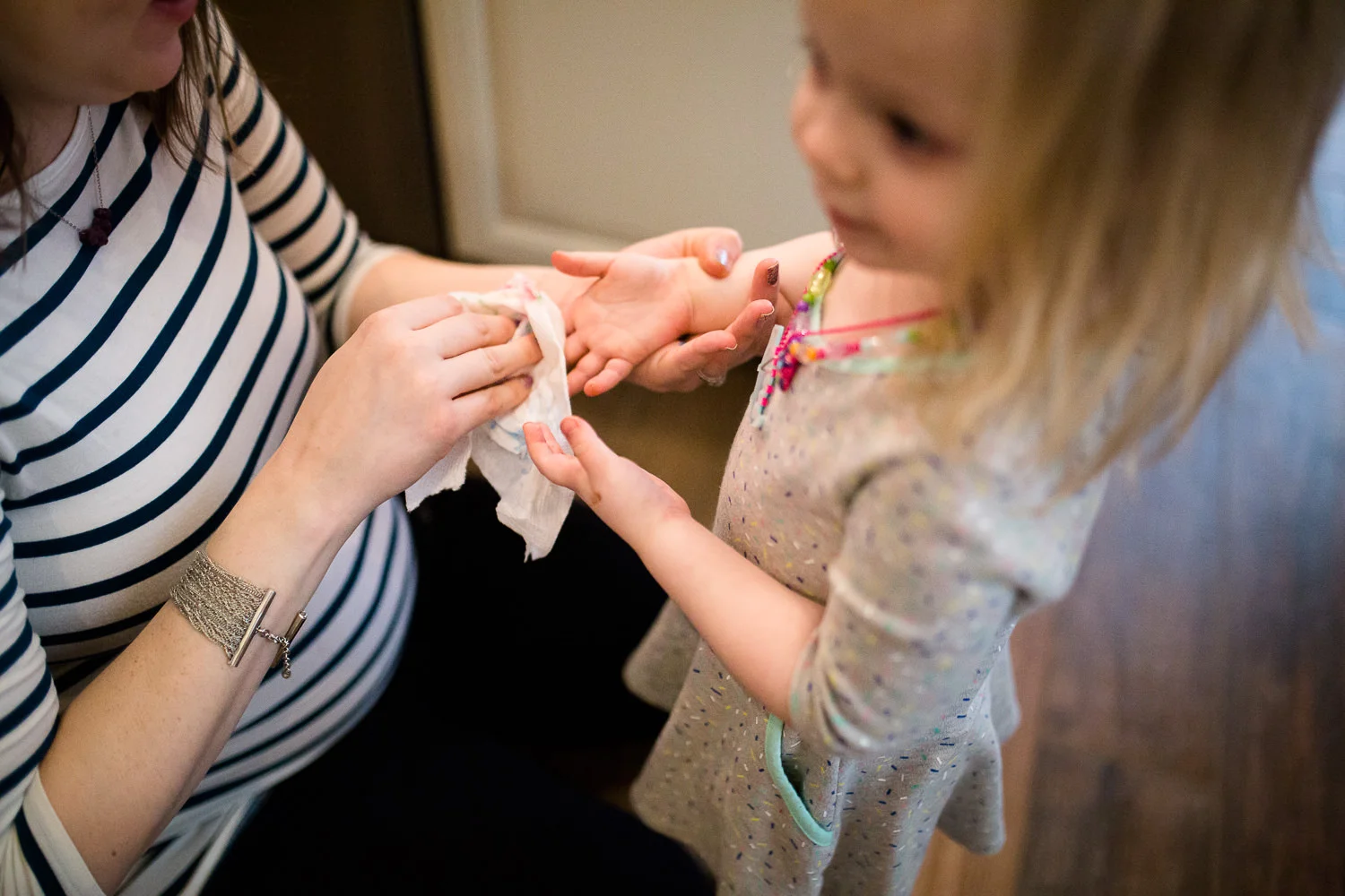 Mom wiping chocolate off of hands of little girl