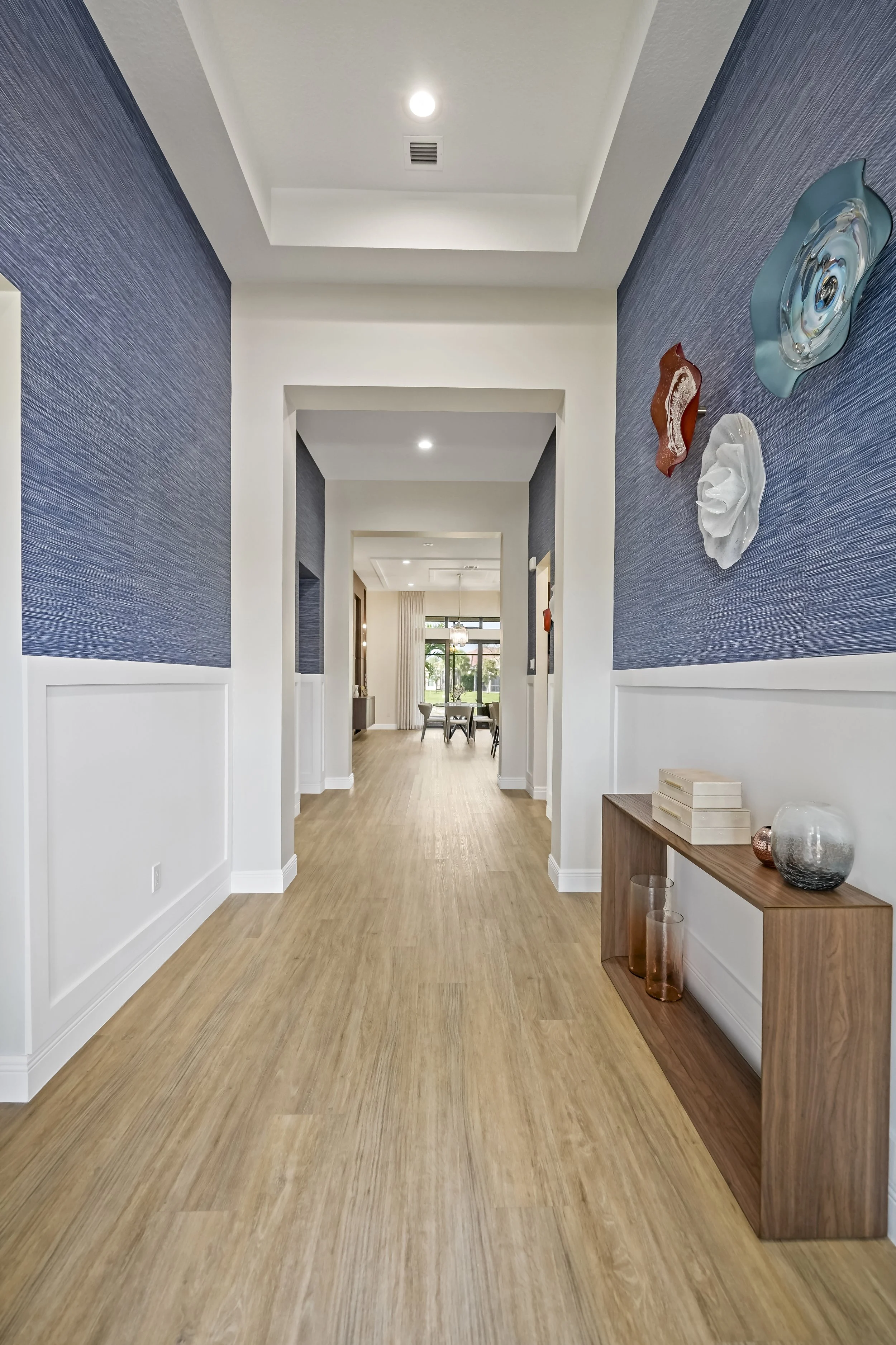 Foyer with custom millwork, wallpaper, furniture, and accessories.