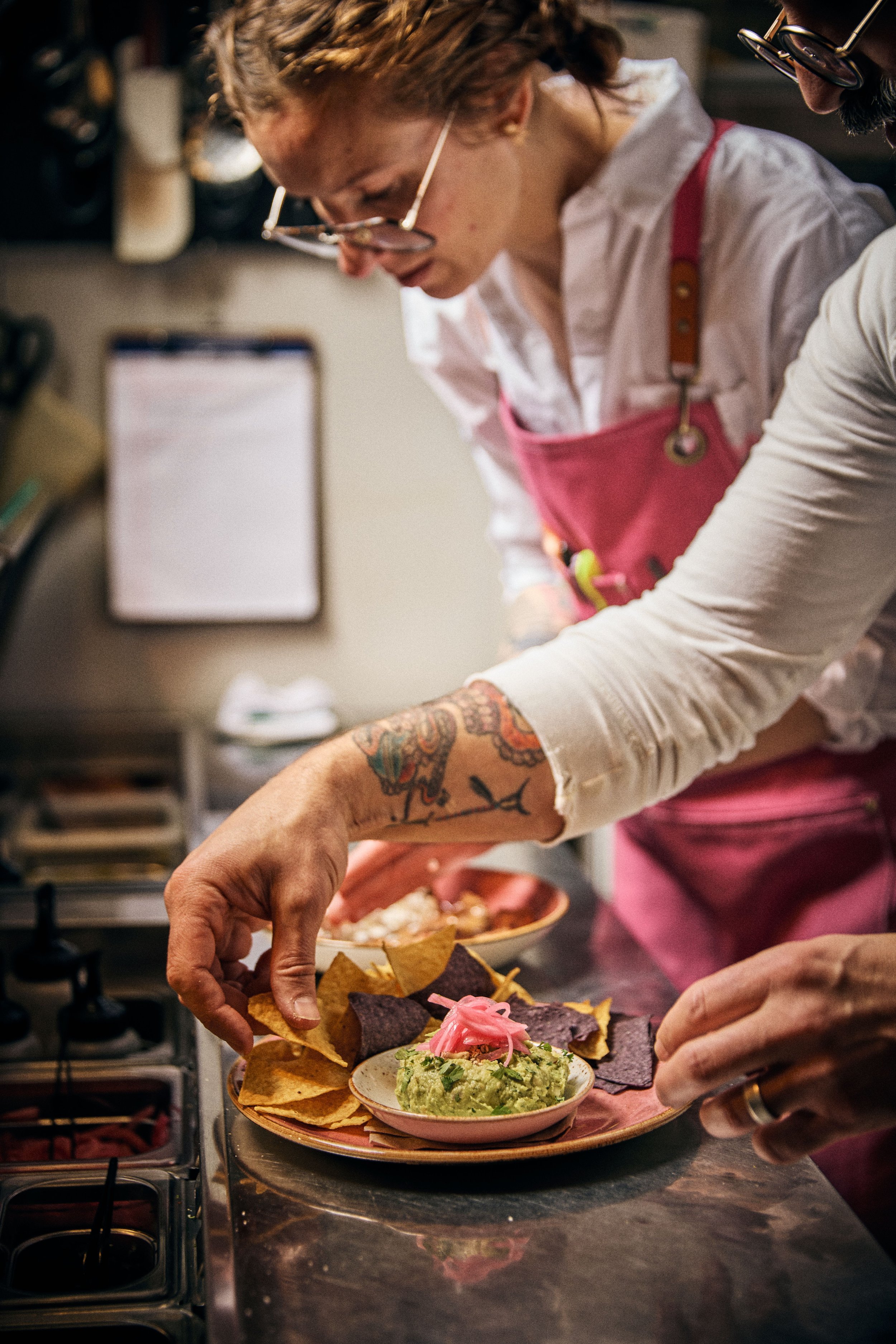 Juli y Juan preparing a plate of nachos with guacamole and pickled onions in at Persimmon Kitchen. One of their consulting clients in Fort Collins Colorado.