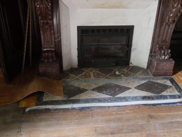 linoleum pulled off to expose beautiful wooden floors and marble hearth.