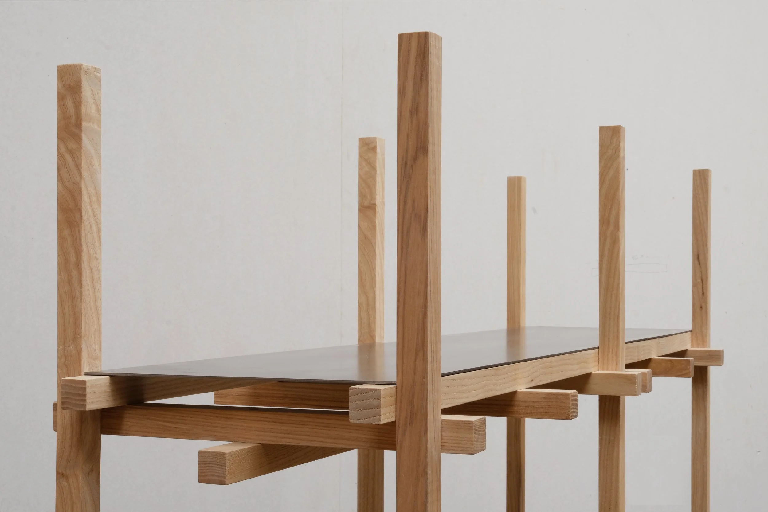 Close-up of modular shelving unit with light wooden frame and dark flat shelves, showcasing layered joinery.