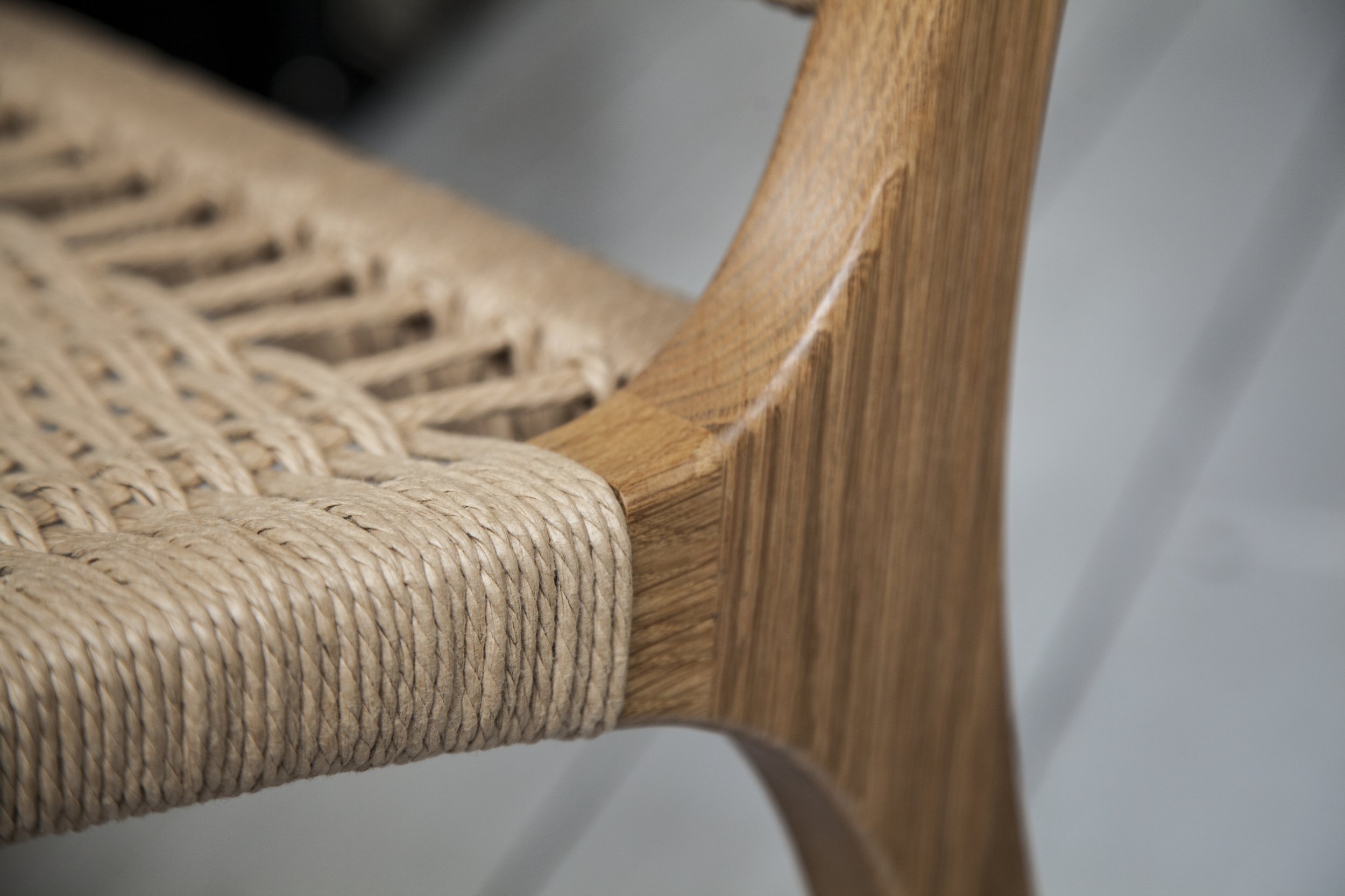 Detail of a woven seat attached to a sculpted wooden frame.