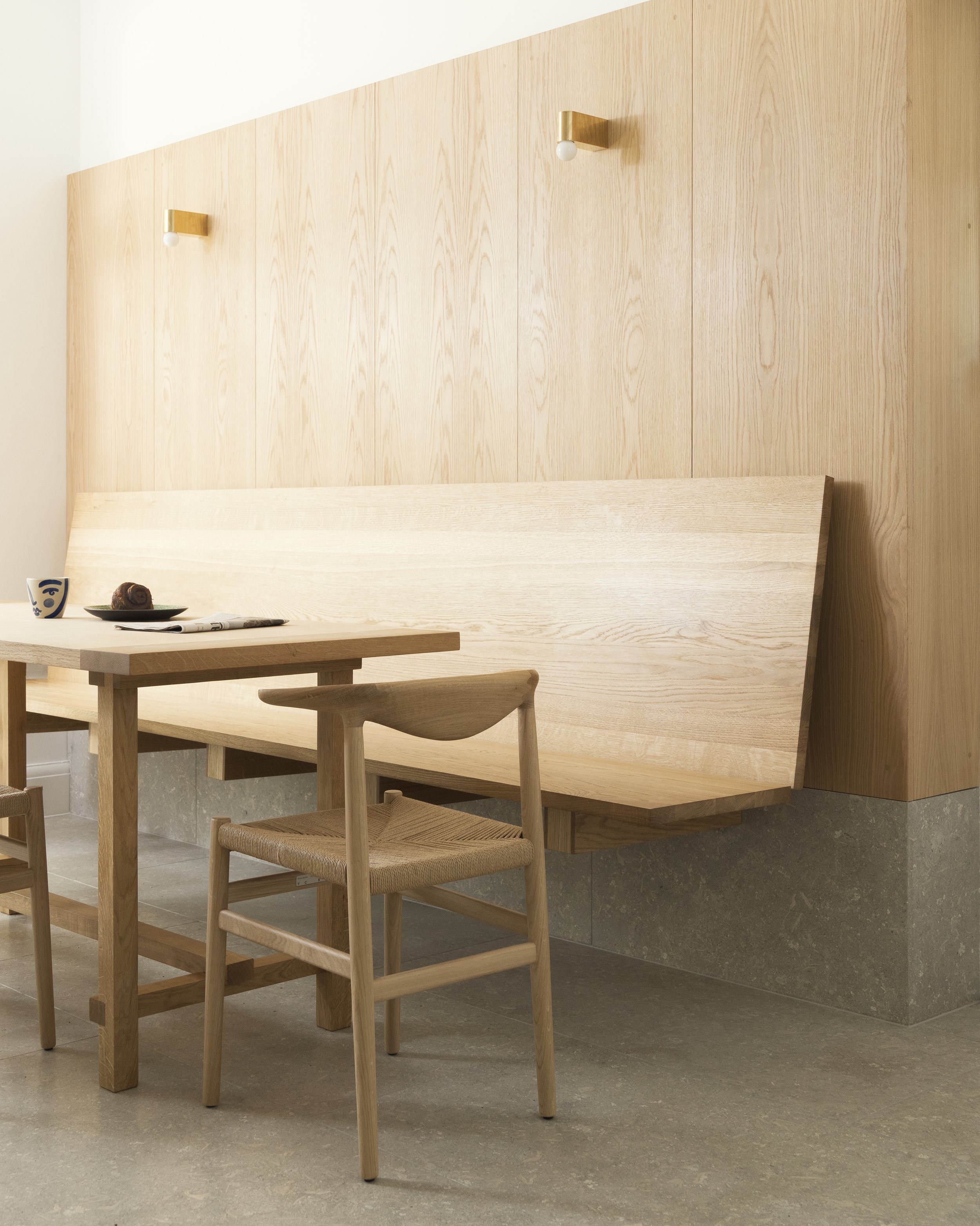 Wall-mounted floating oak bench paired with a wooden dining table and woven chairs.
