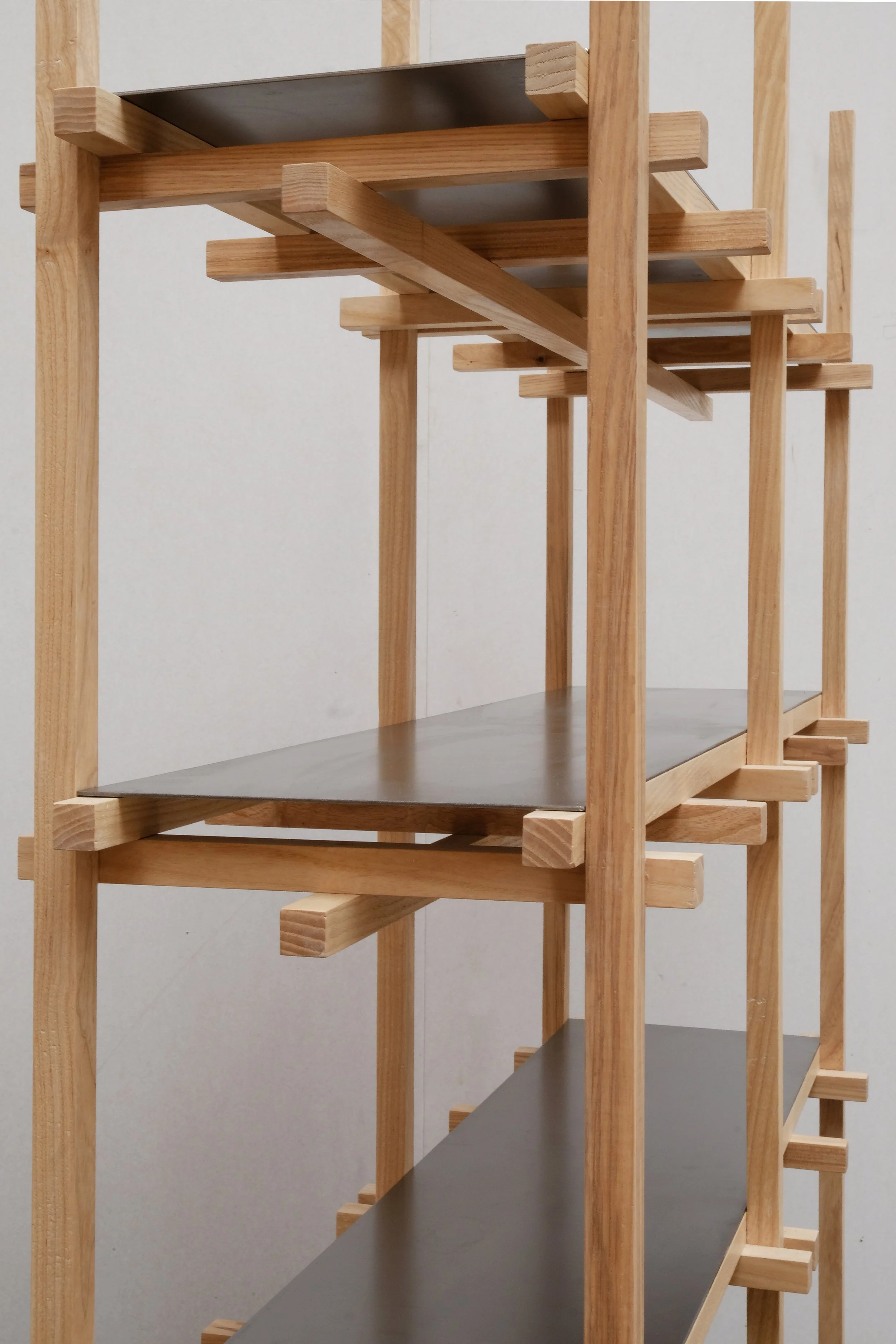 Detail view of a wooden shelving unit featuring intersecting natural wood supports and dark flat shelves.