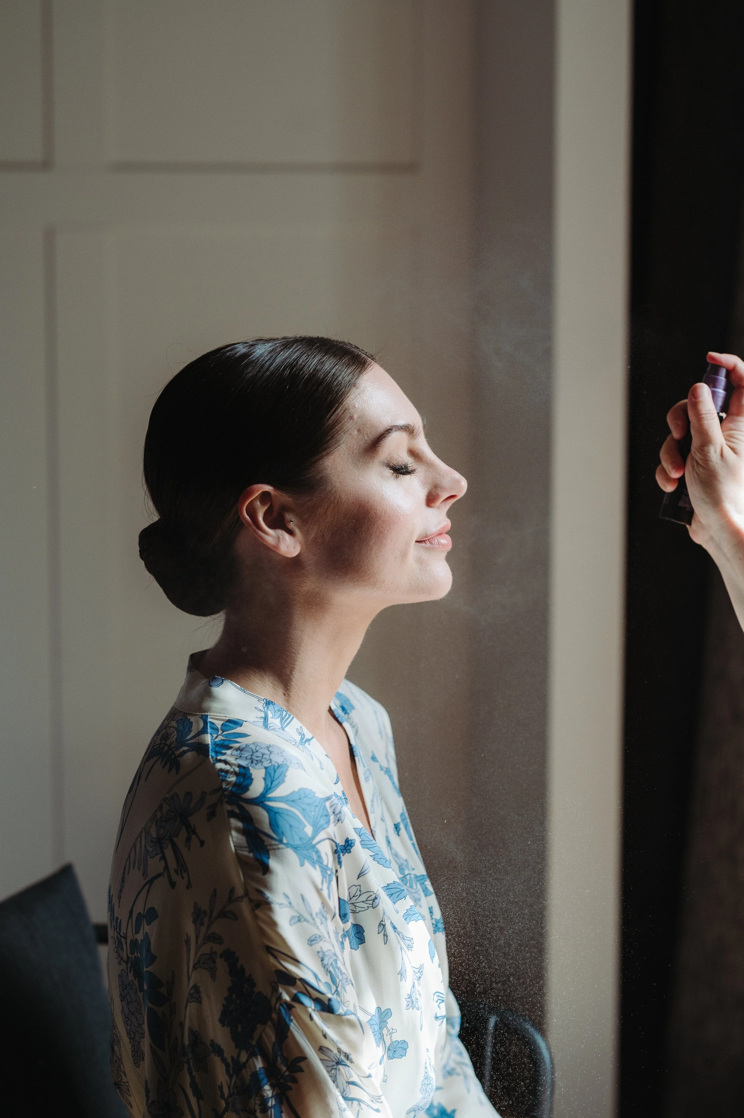Bride getting ready by the window with soft natural bridal makeup in Barcelona.