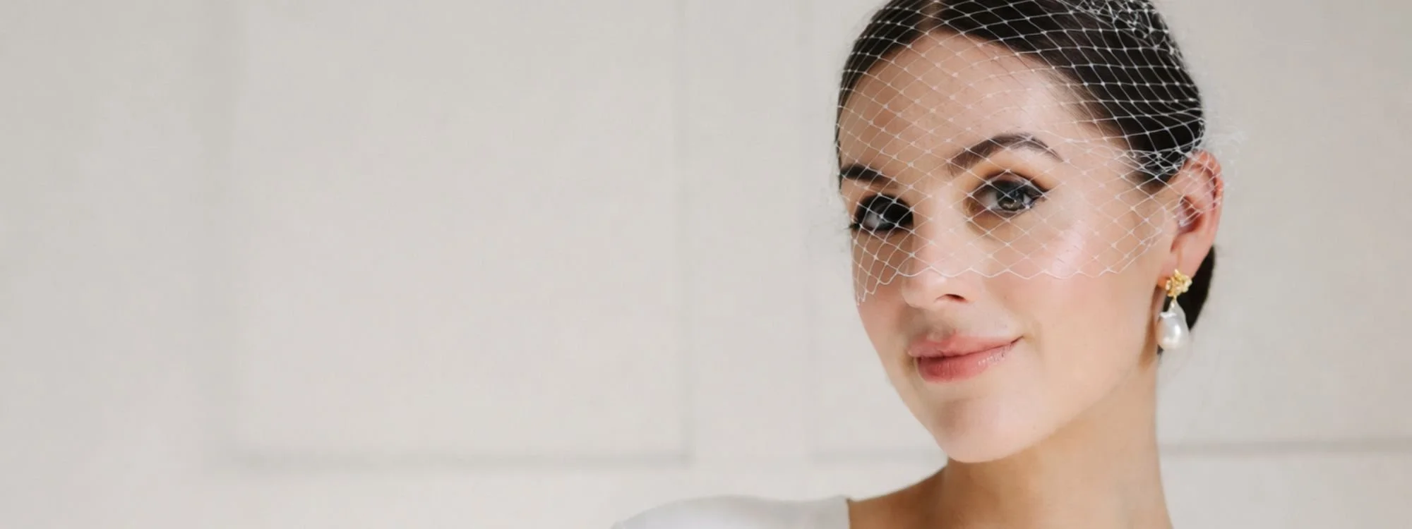Bride with natural and elegant makeup wearing a delicate birdcage veil in Barcelona.
