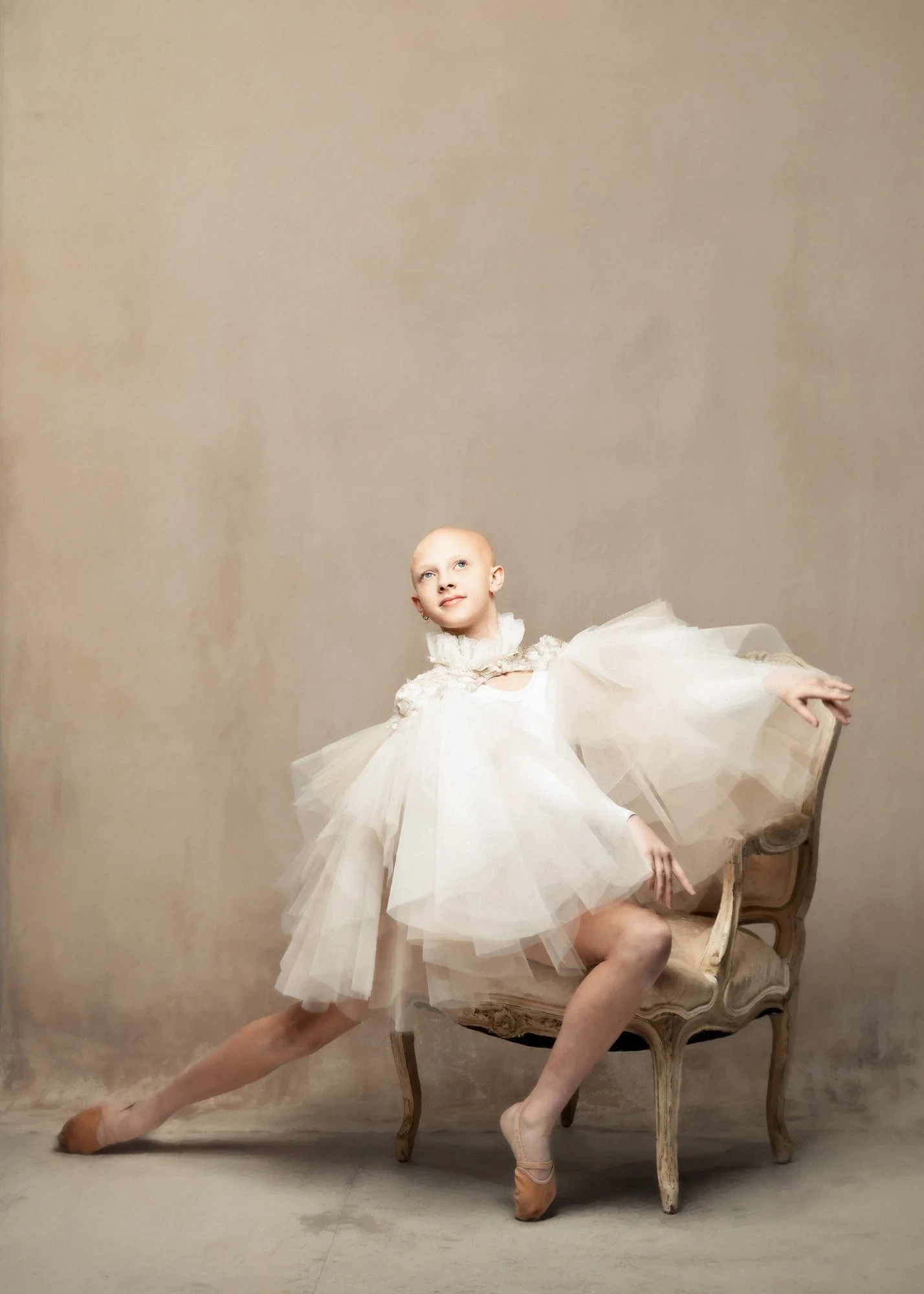 studio portrait of a young dancer sitting in a chair wearing a tulle cape, photographed by Nicole Mills