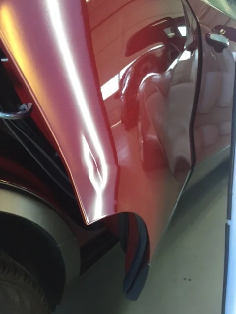 Red vehicle panel before paintless dent repair
