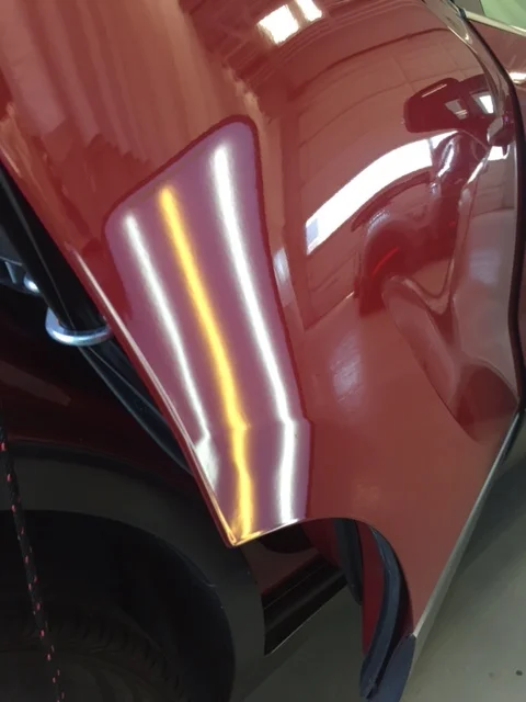 Red vehicle panel after paintless dent repair