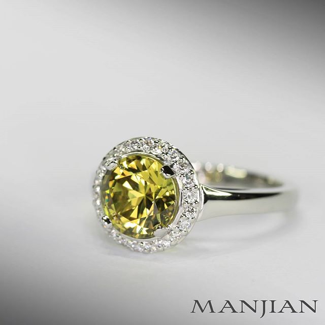 An Australian untreated natural yellow sapphire, cut in Queensland to the proportions of a triple excellent graded round brilliant cut diamond and set in a custom made ring in platinum with a diamond halo border.