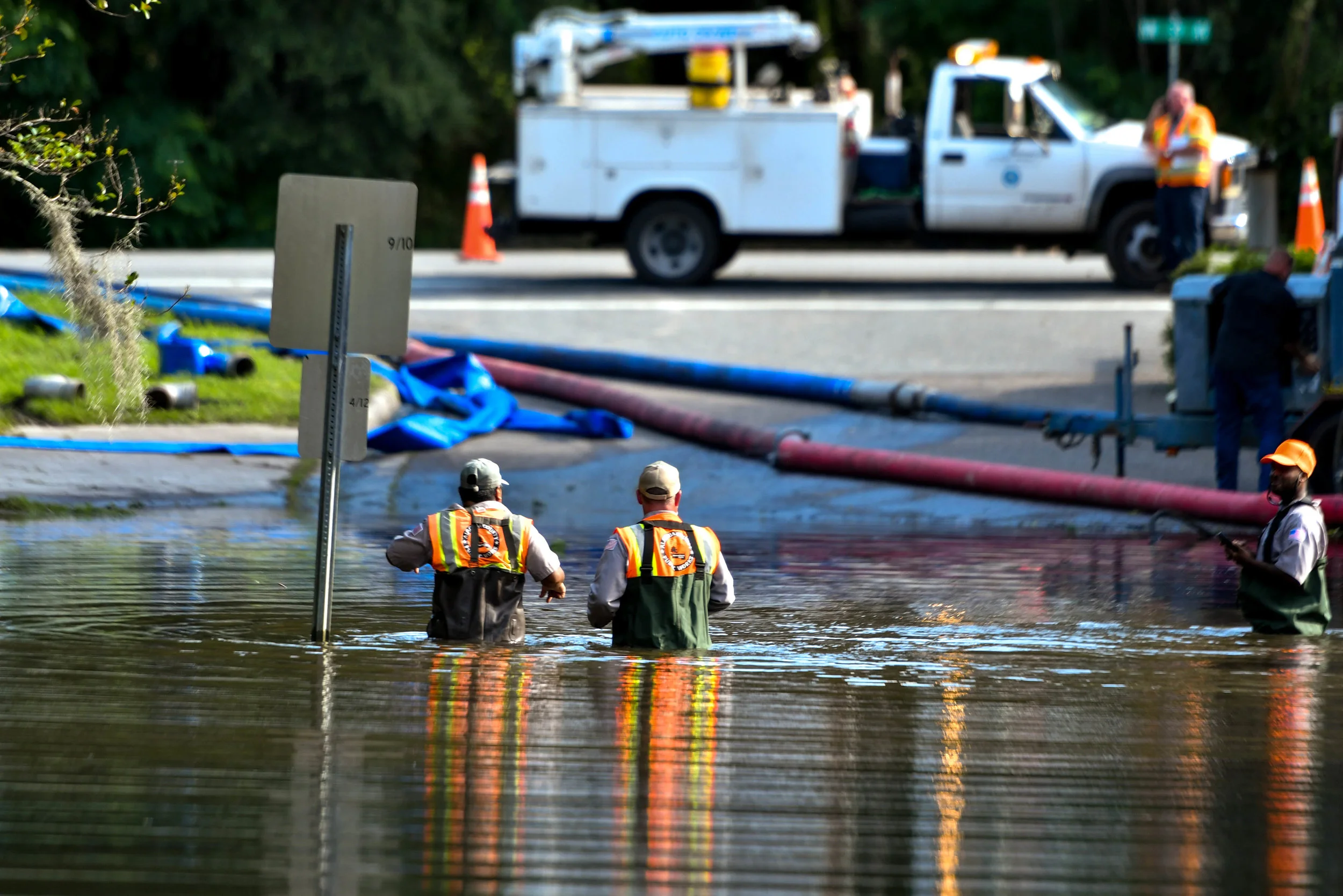 Workers walk out of the excess stormwater at the entrance of the Robin Lane Neighborhood. It took more than two days to make the road accessible. (Grace King / WUFT News)
