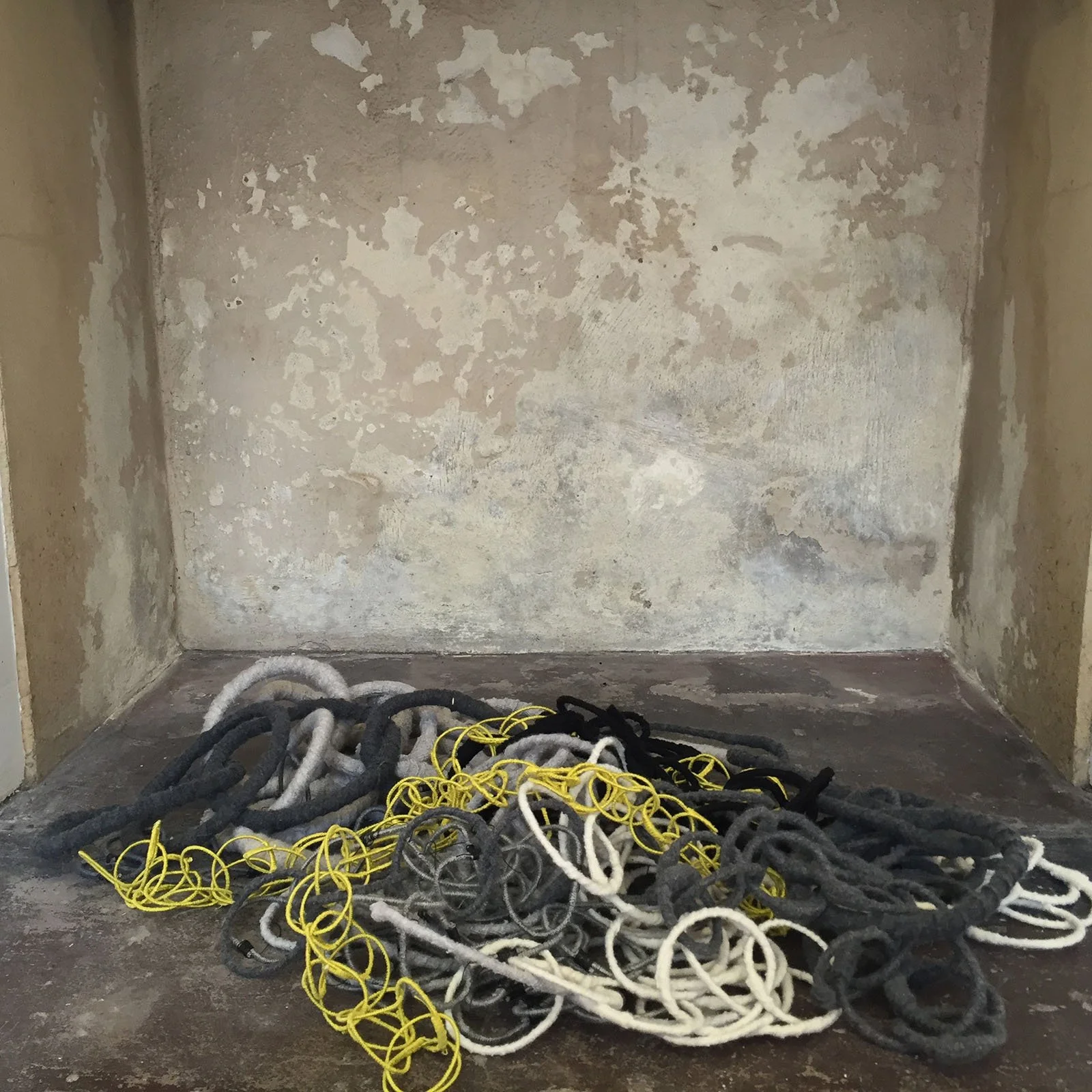 Metal rings wrapped in knitted fabric lie in a stone fireplace