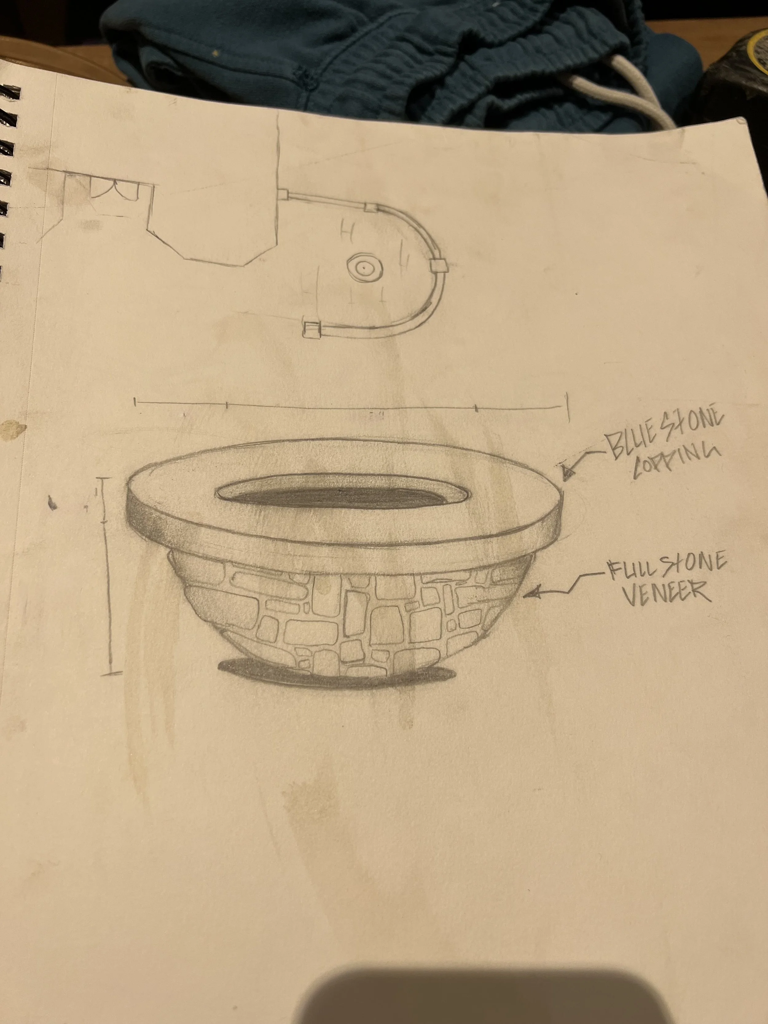 Sketch of a stone bowl with a flat rim, labeled as a "full stone veneer," and surrounded by hand-written notes indicating "blue stone coping." The drawing shows a detailed, textured stone pattern on the bowl's exterior.