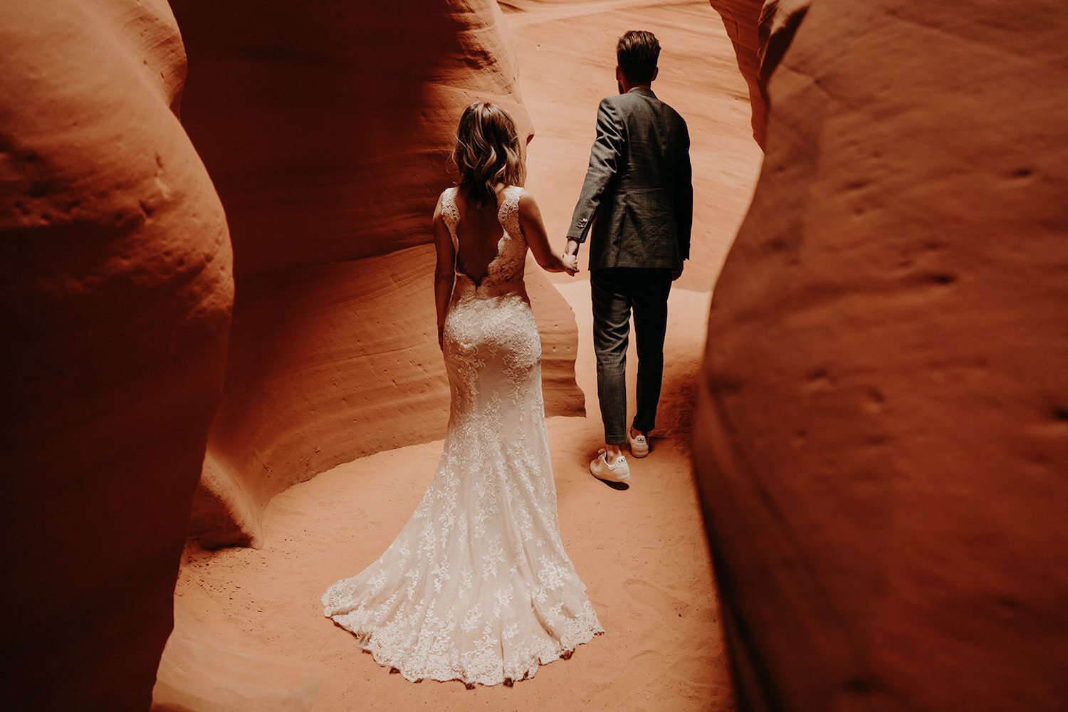 Bride and groom hold hands while standing in a canyon at Antelope Canyon in Arizona during their AZ elopement by Promise Mountain