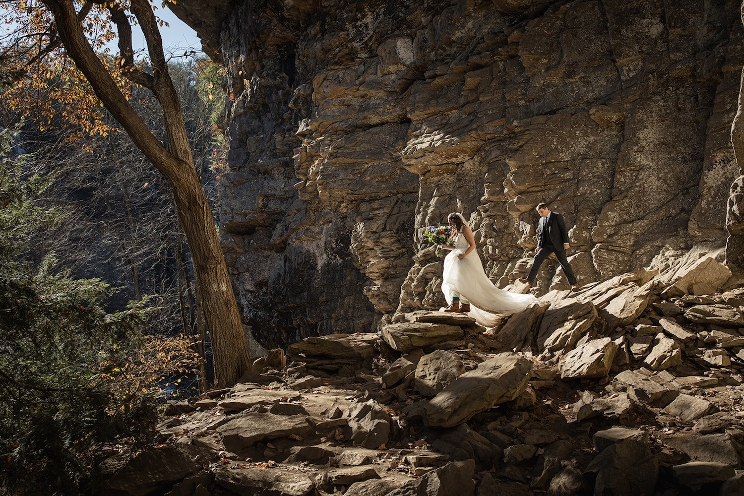 Bride and groom trek along a rock formation by Promise Mountain