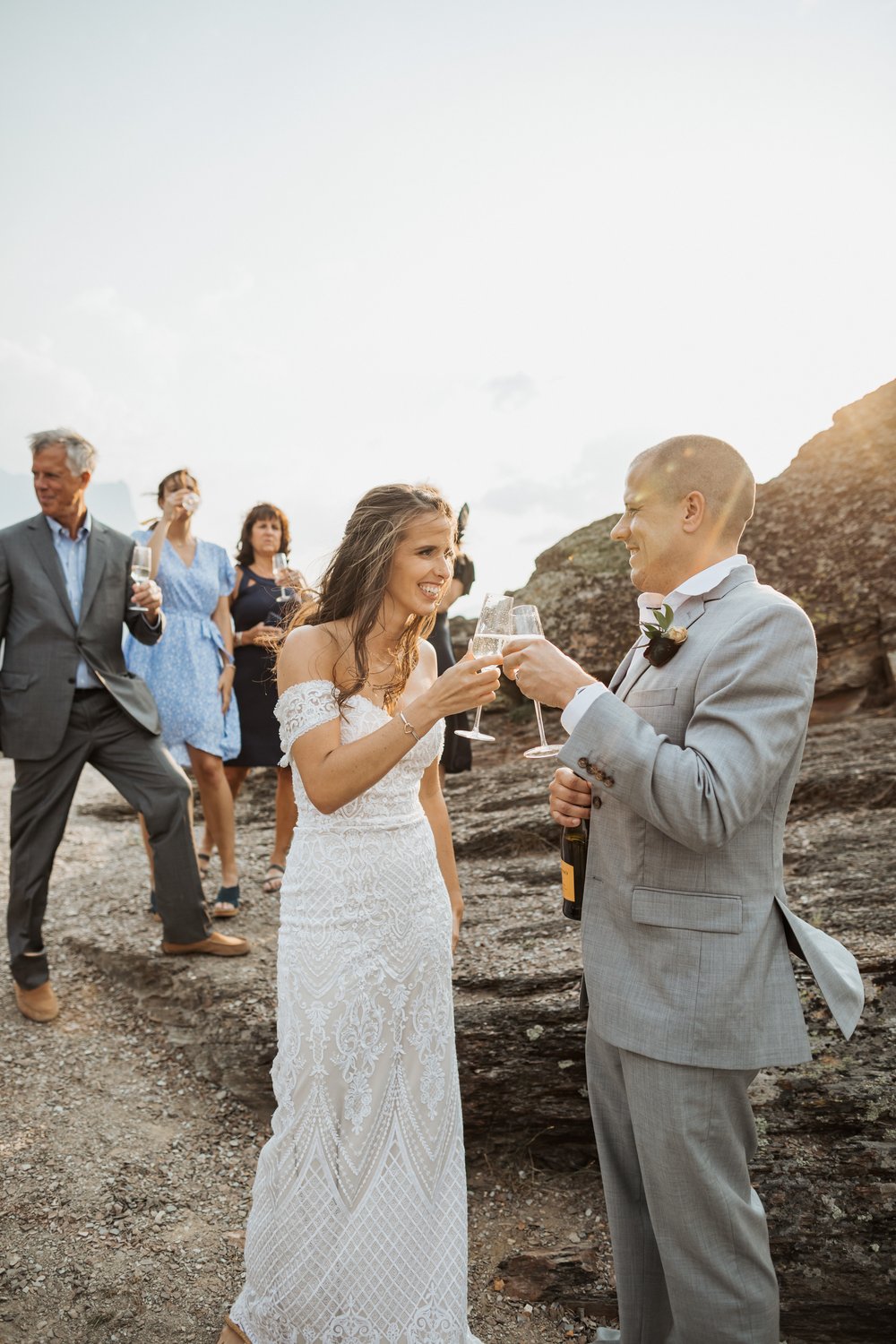 Bride and groom toast their glasses of champagne with their guests behind them
