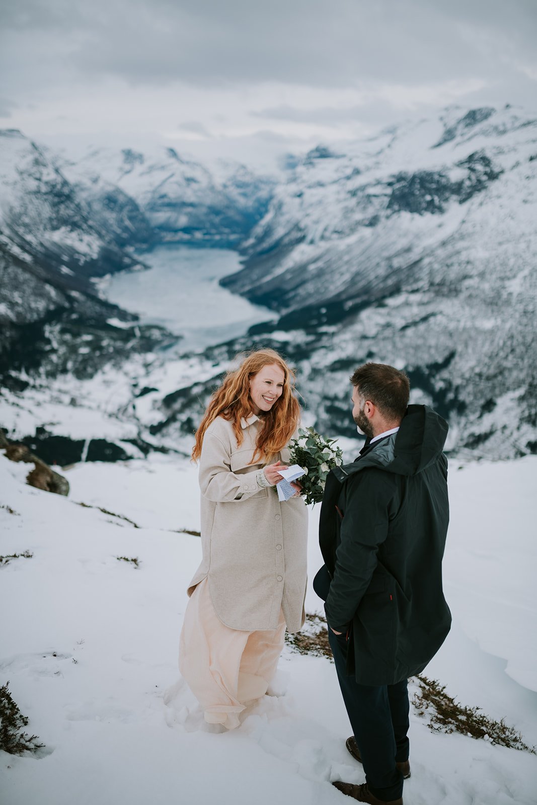 What is Eloping and Is It For You? Couple smiling at each other while at a snowy mountain for their elopement shoot with Promise Mountain