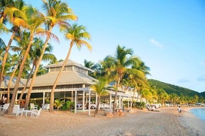 A lovely covered patio on the beach, framed by palm trees.
