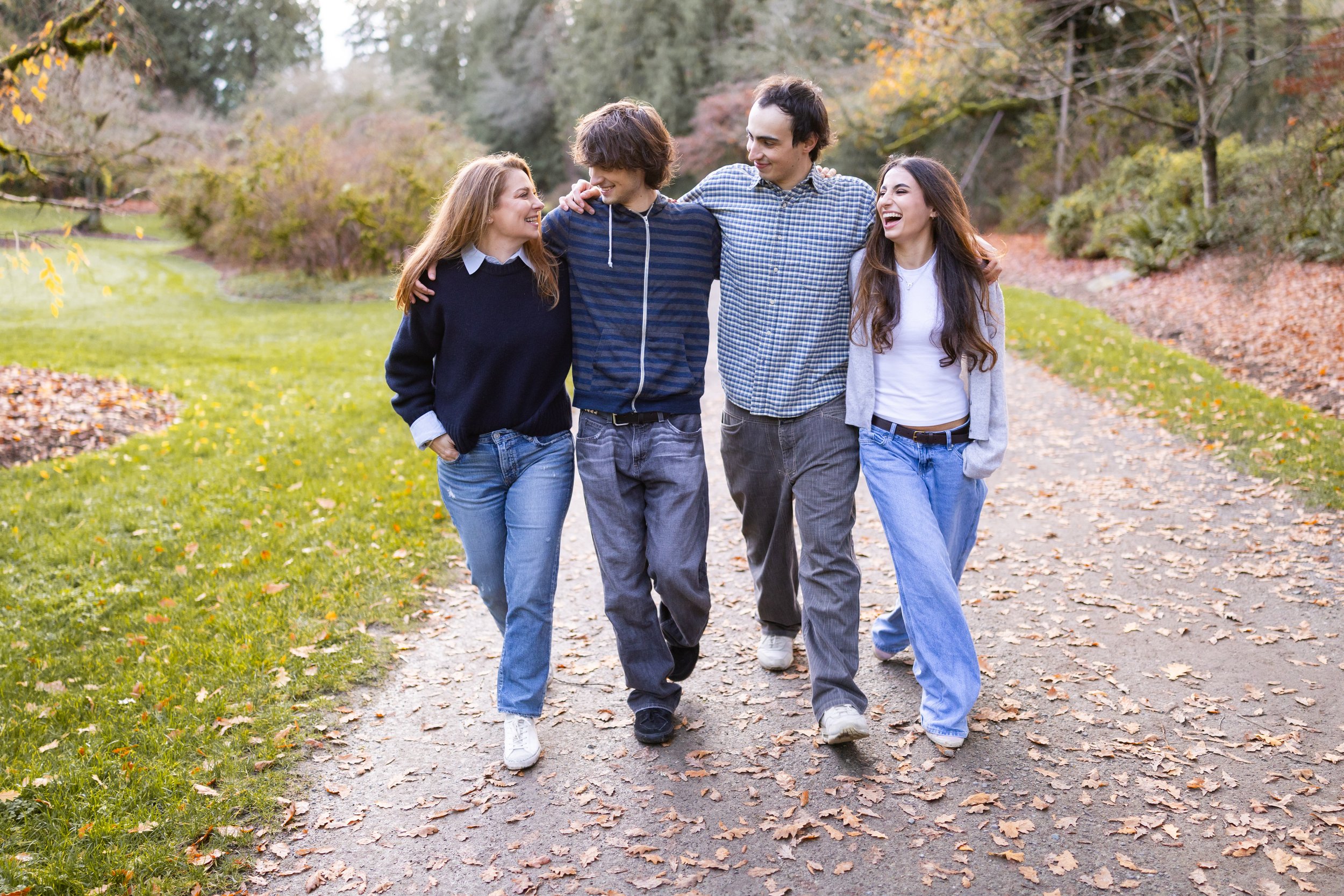 Four young adults walking in a park in autumn, smiling and talking.