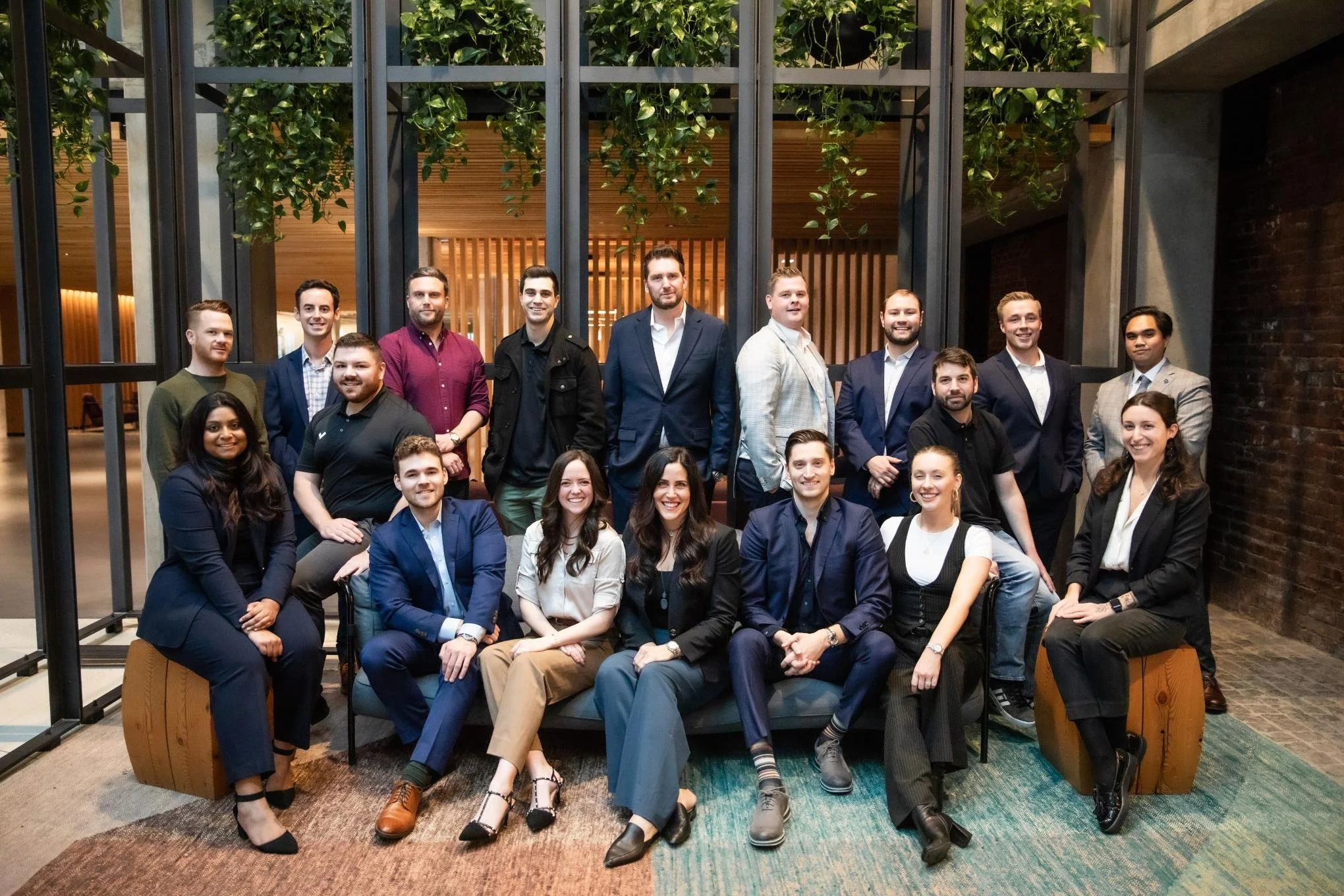 Group of diverse professionals for a corporate photo in an indoor setting with green plants and wooden accents.