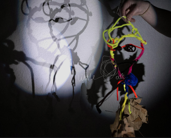 Child holding a wire sculpture exploring shadows