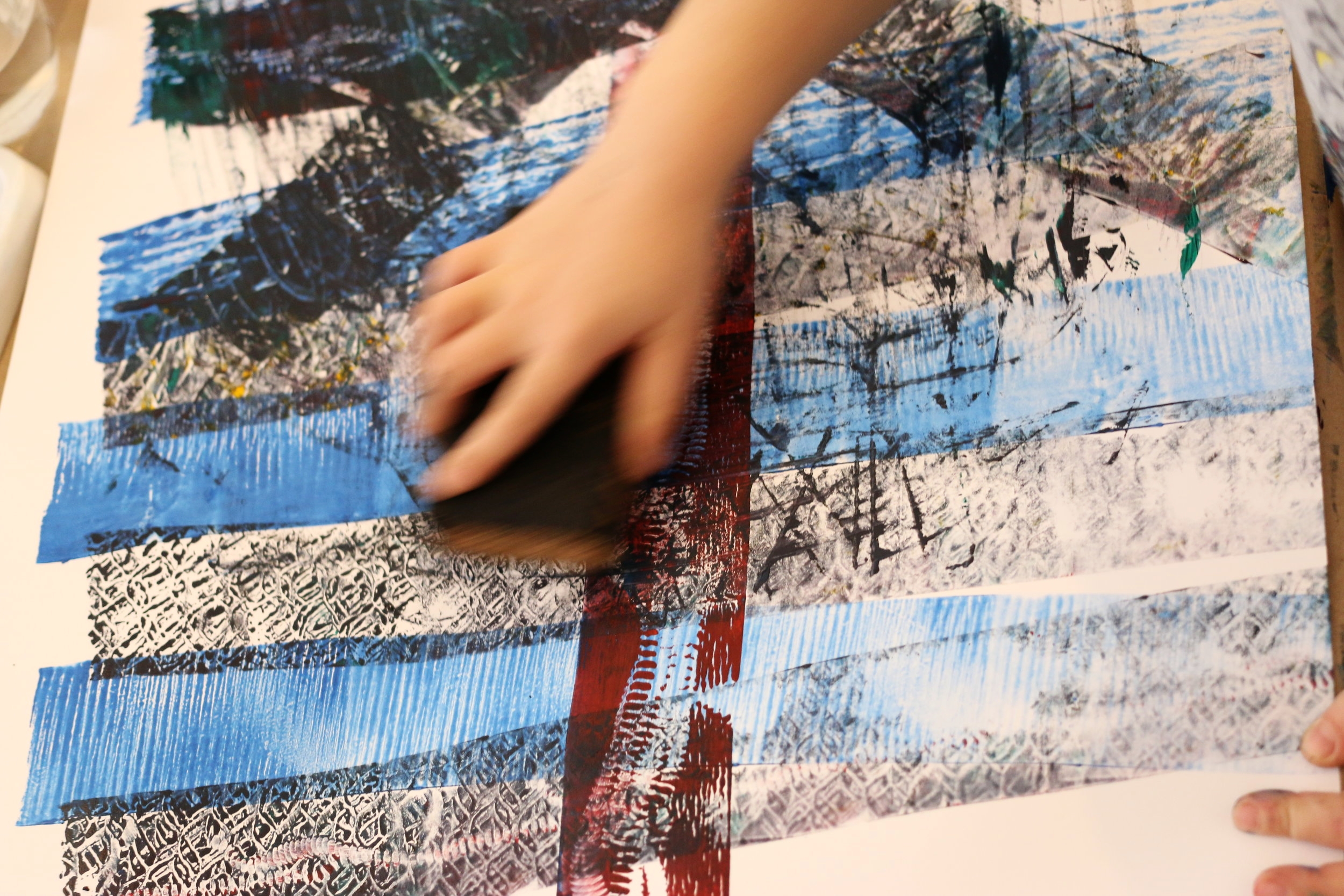 Child's hand rolling in making a print during a kid's art workshop