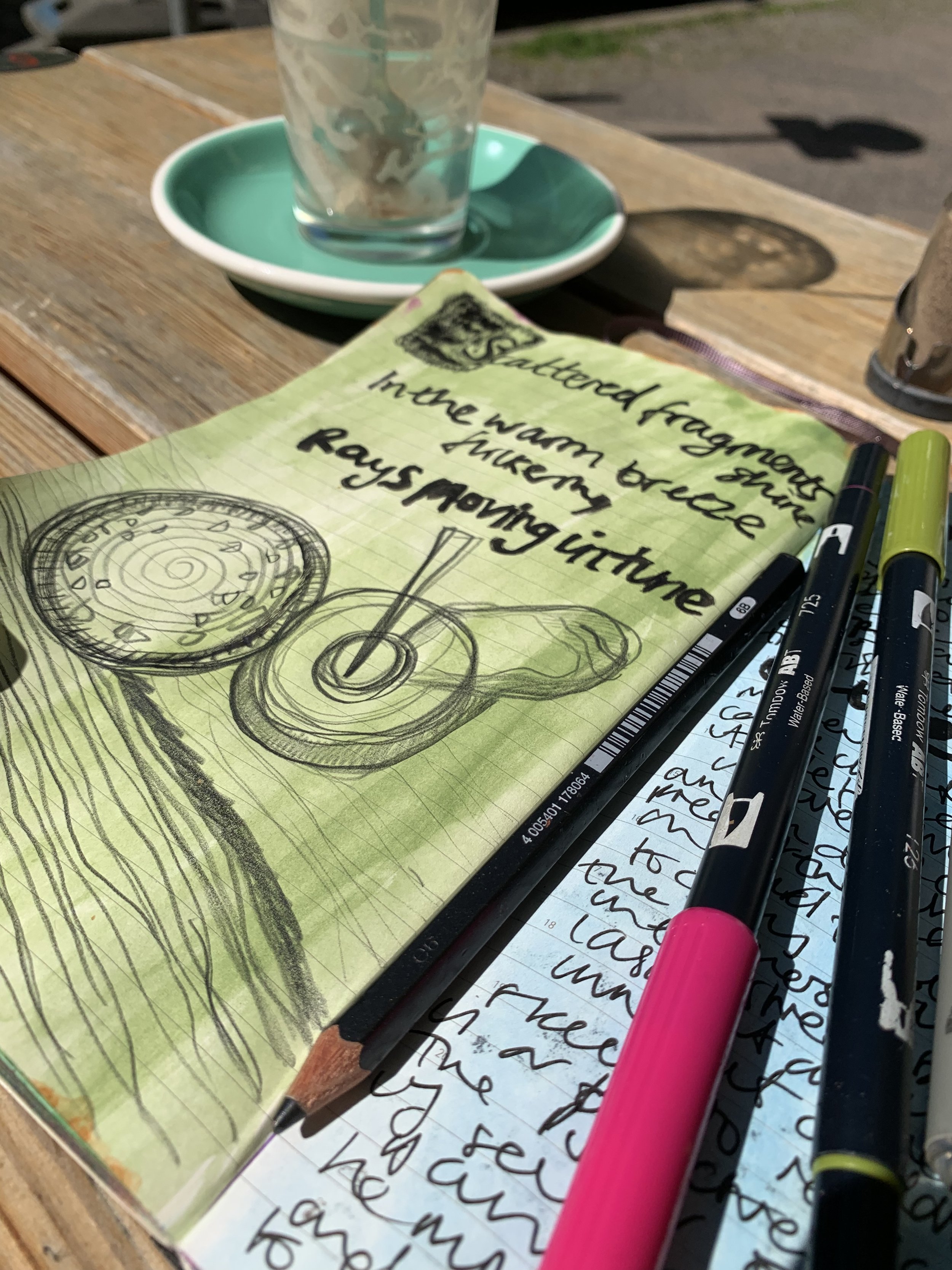Journal open in a cafe with free writing and cup doodle