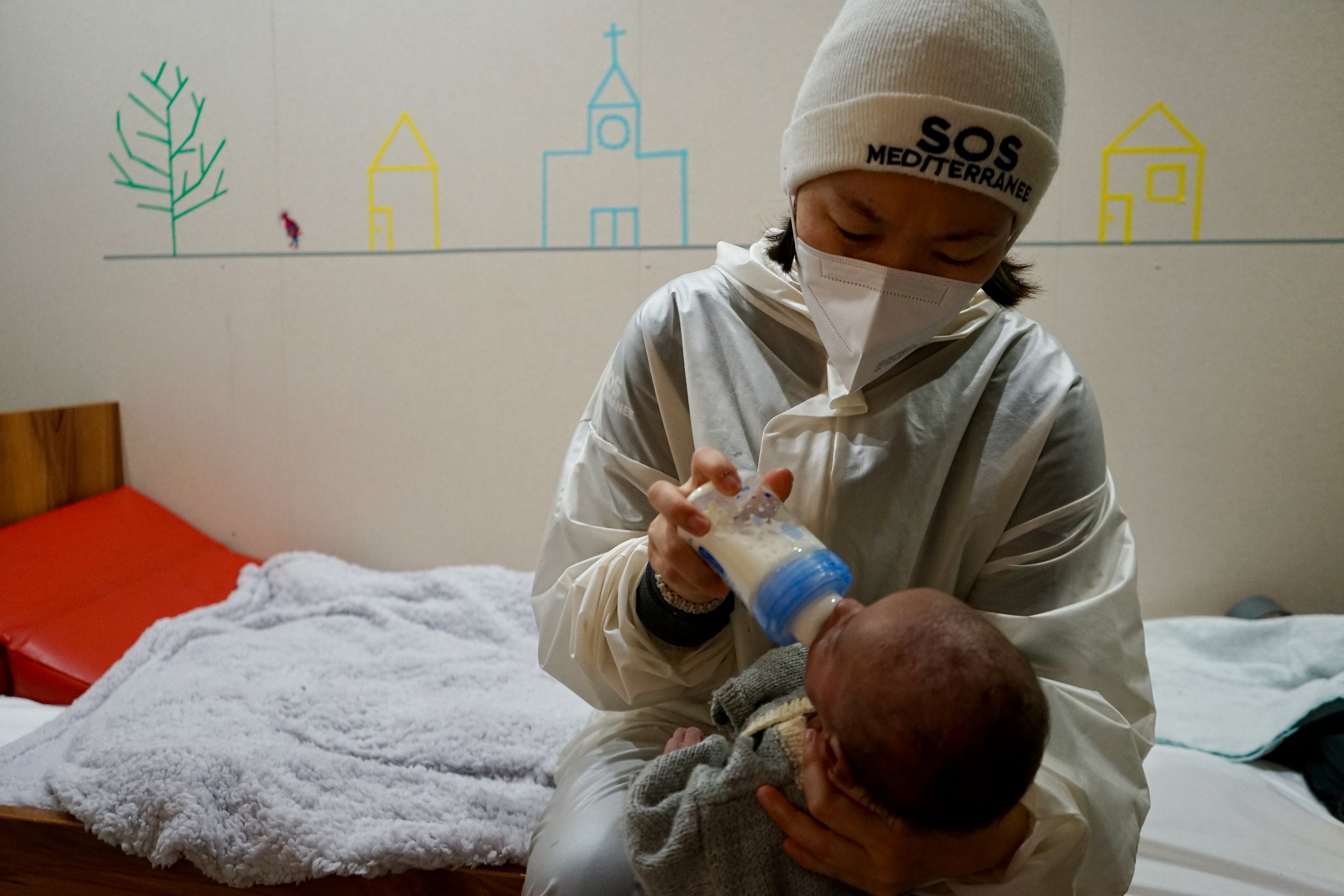 Marina, SOS MEDITERRANEE crew member and a midwife, gives a 4-week-old baby boy milk to drink. 