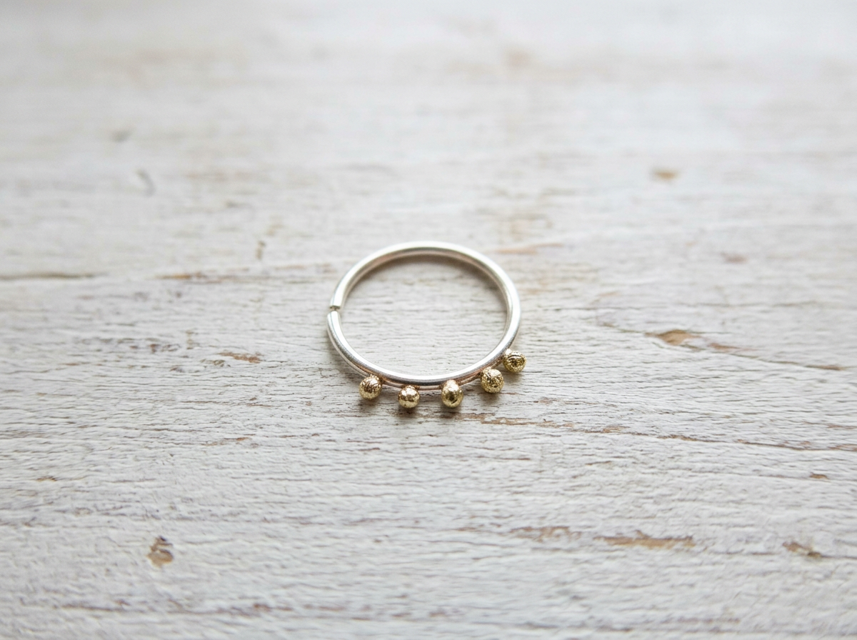 Handcrafted recycled sterling silver conch hoop earring with solid 9ct gold spheres on white wooden background.