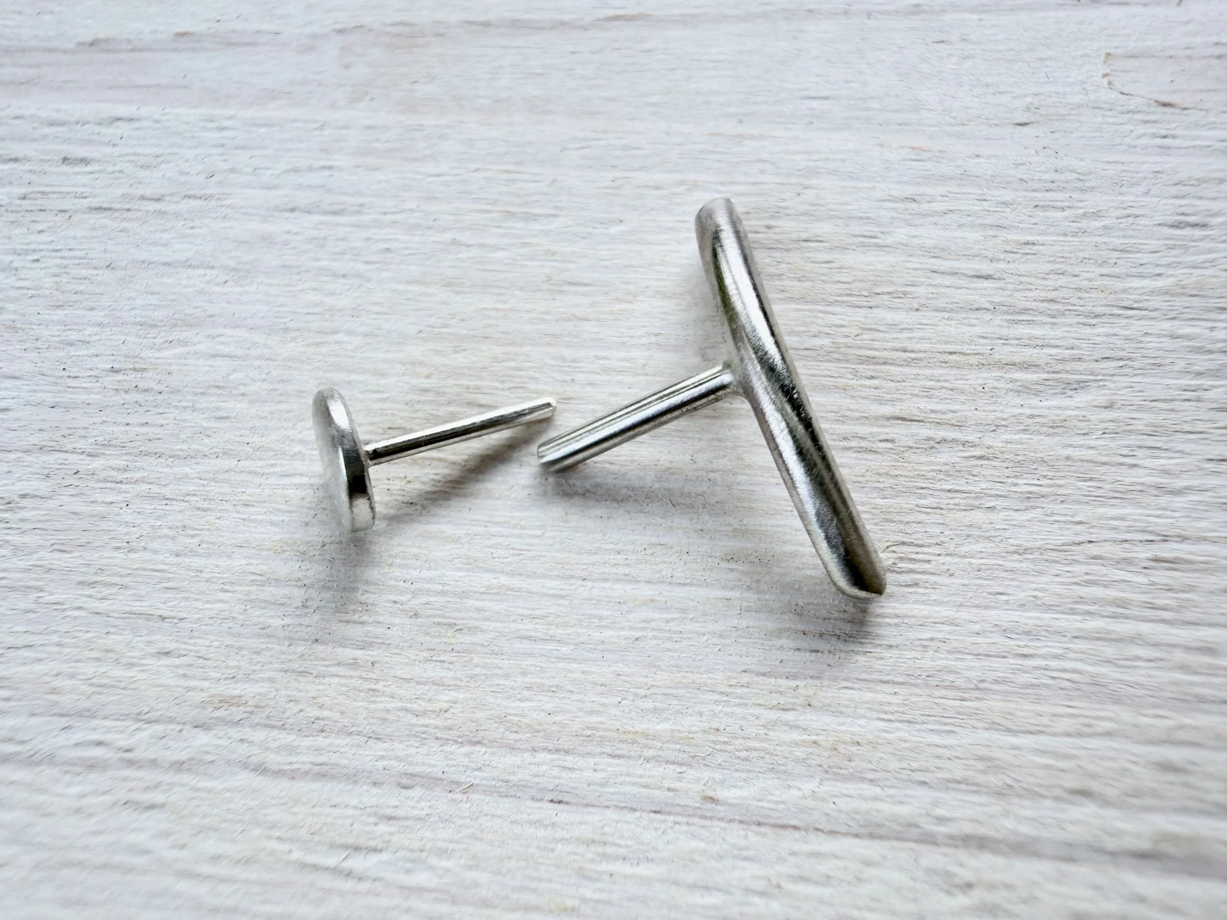 eco silver conch earring with threadless press fit post on white wood background
