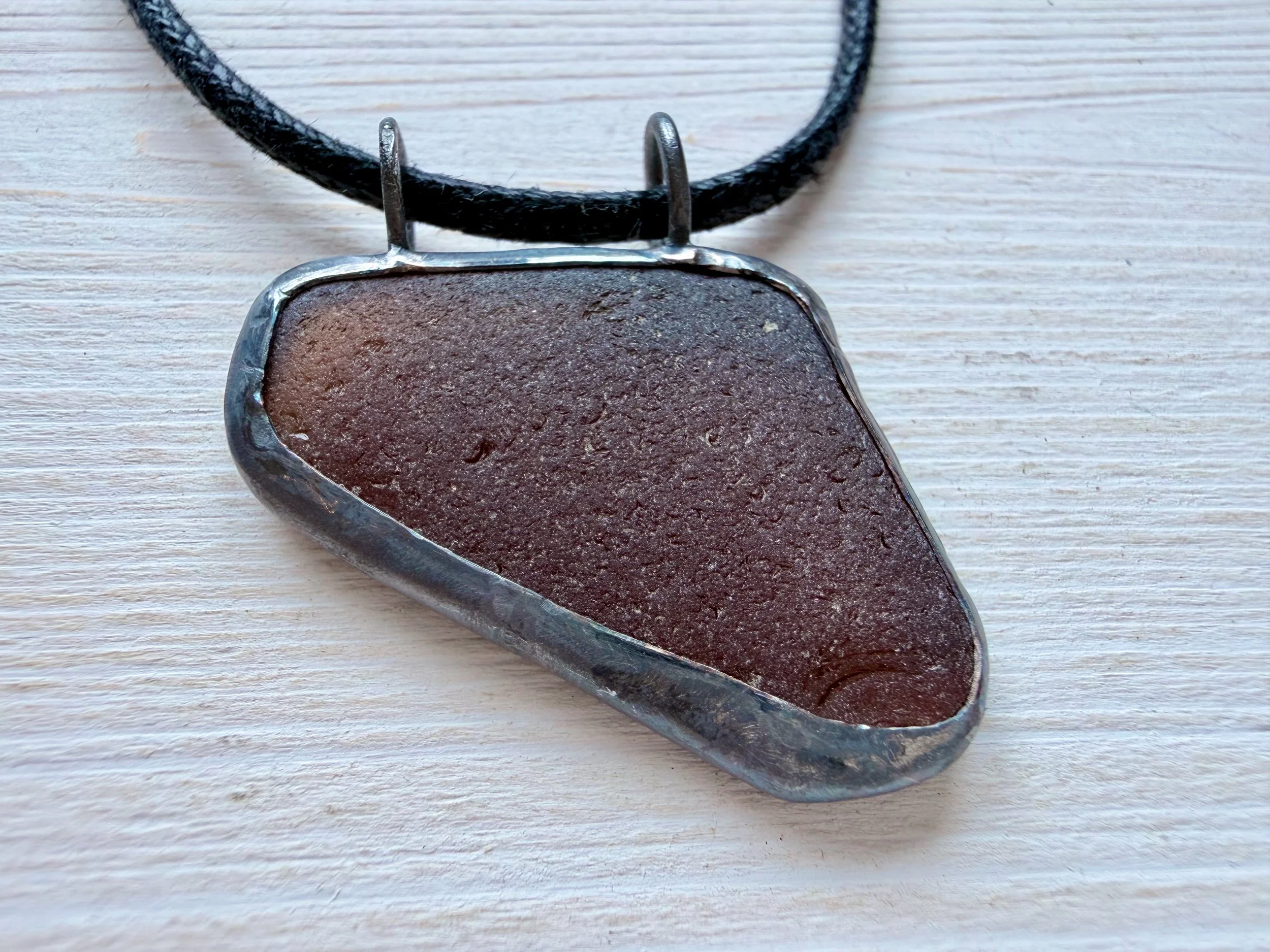 coffe-brown-sea-glass-pendant-oxidised-victoria-grace-studaClose-up of one of a kind handcrafted triangular amber sea glass piece with double top jump rings and antiqued silver finish.io_1786.jpeg