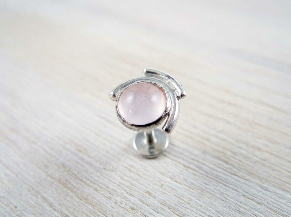 Handcrafted recycled sterling silver celestial rose quartz sun and moon conch stud earring on white wooden background.