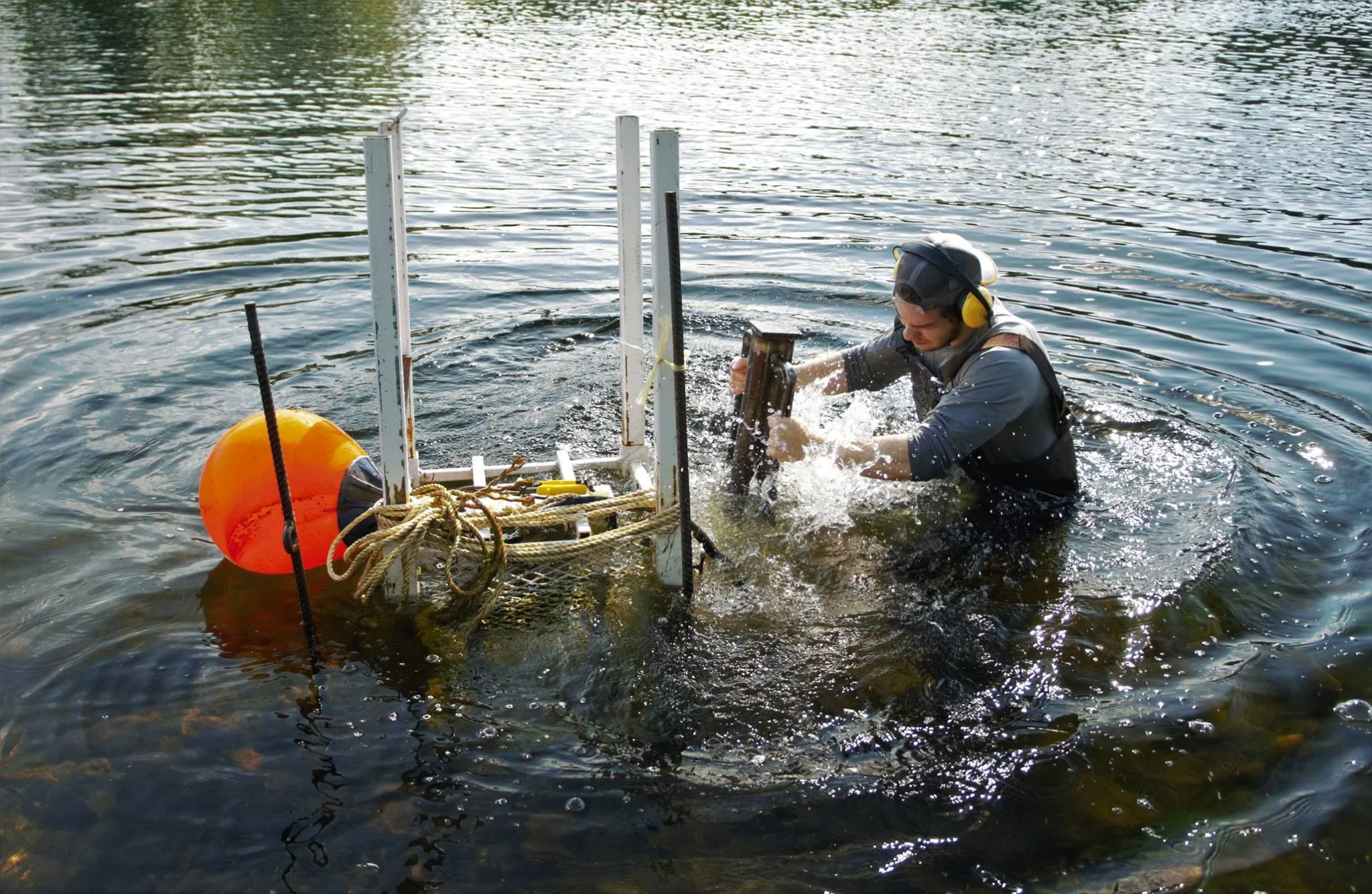 A CAST member pounding rebar in the Miramichi River to secure a sonar camera to allow accurate counting of salmon - Photographed by Jani Helminen