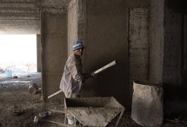 Egyptian construction worker spreads concrete on walls of soon-to-be villa. Photo: Jihad Abaza
