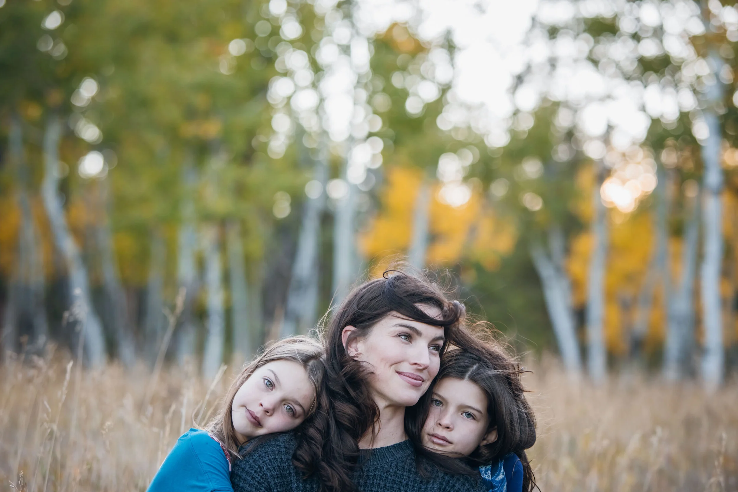 A woman with two children in a field during autumn.