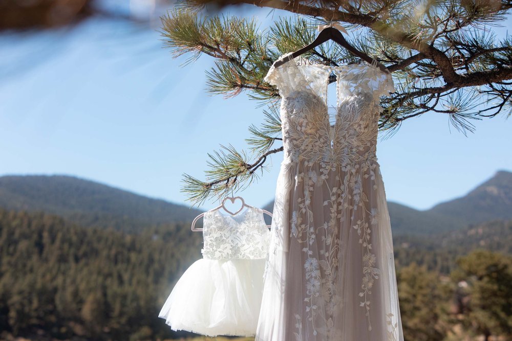 Mom and daughter wedding dress and flower girl dress hanging at Deer Creek Valley Ranch