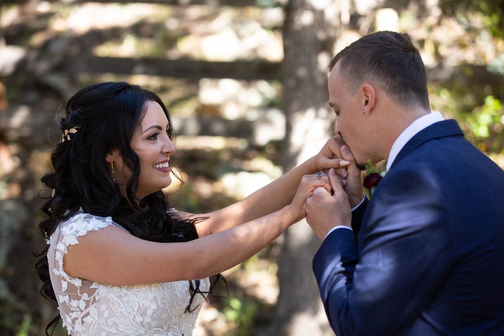 Groom kissing the bride's hands at their first look at Deer Creek Valley Ranch