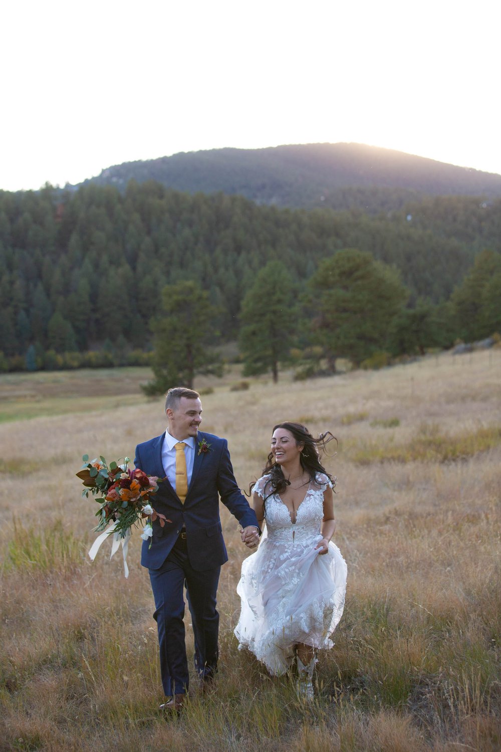 Bride in groom in the fields of at Deer Creek Valley Ranch at sunset