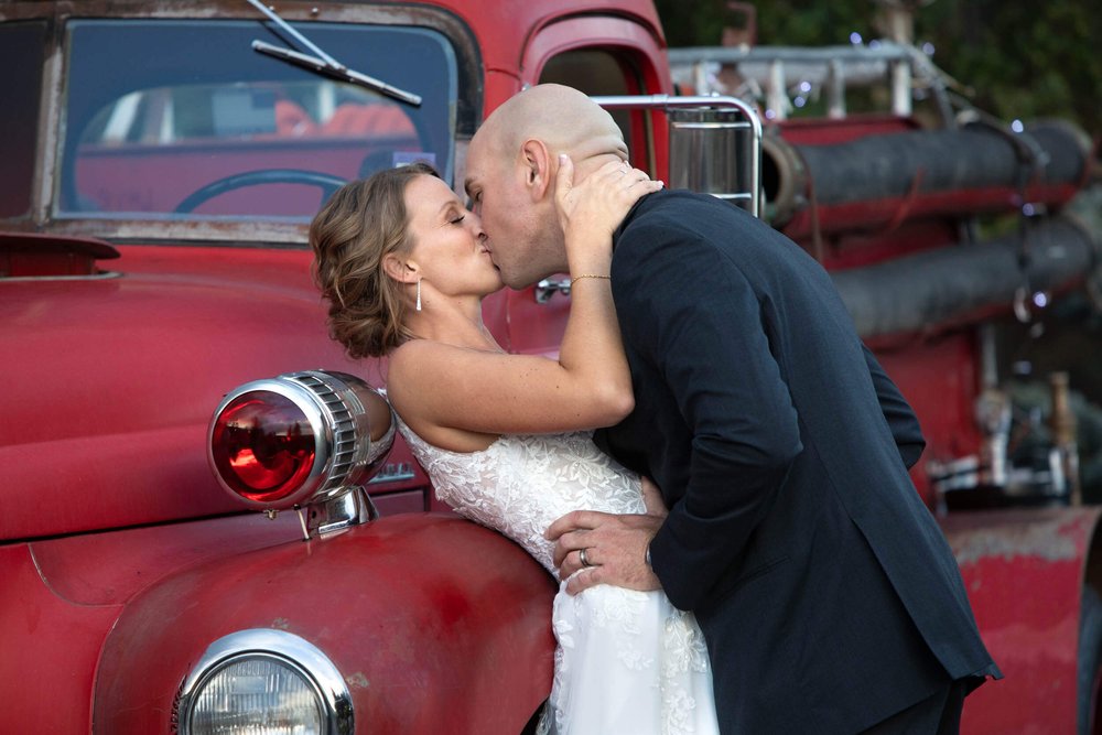 Bride and Groom kissing against a vintage firetruck at Spruce Mountain Ranch