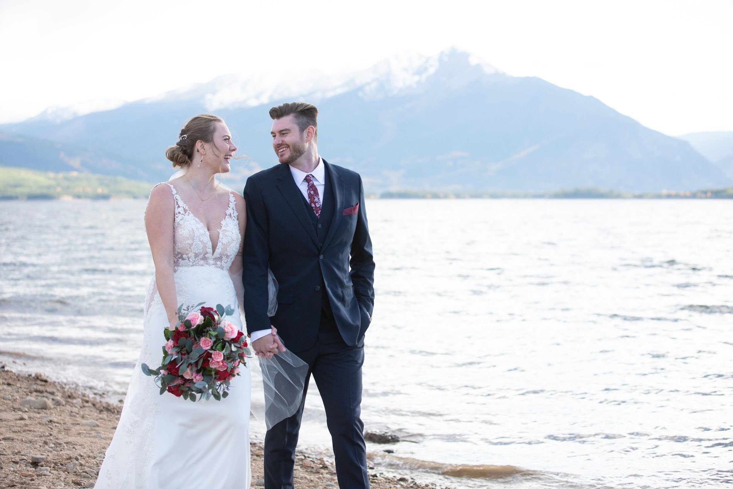 Bride and Groom walking along a lake with mountains  in Colorado by CliftonMarie Photography